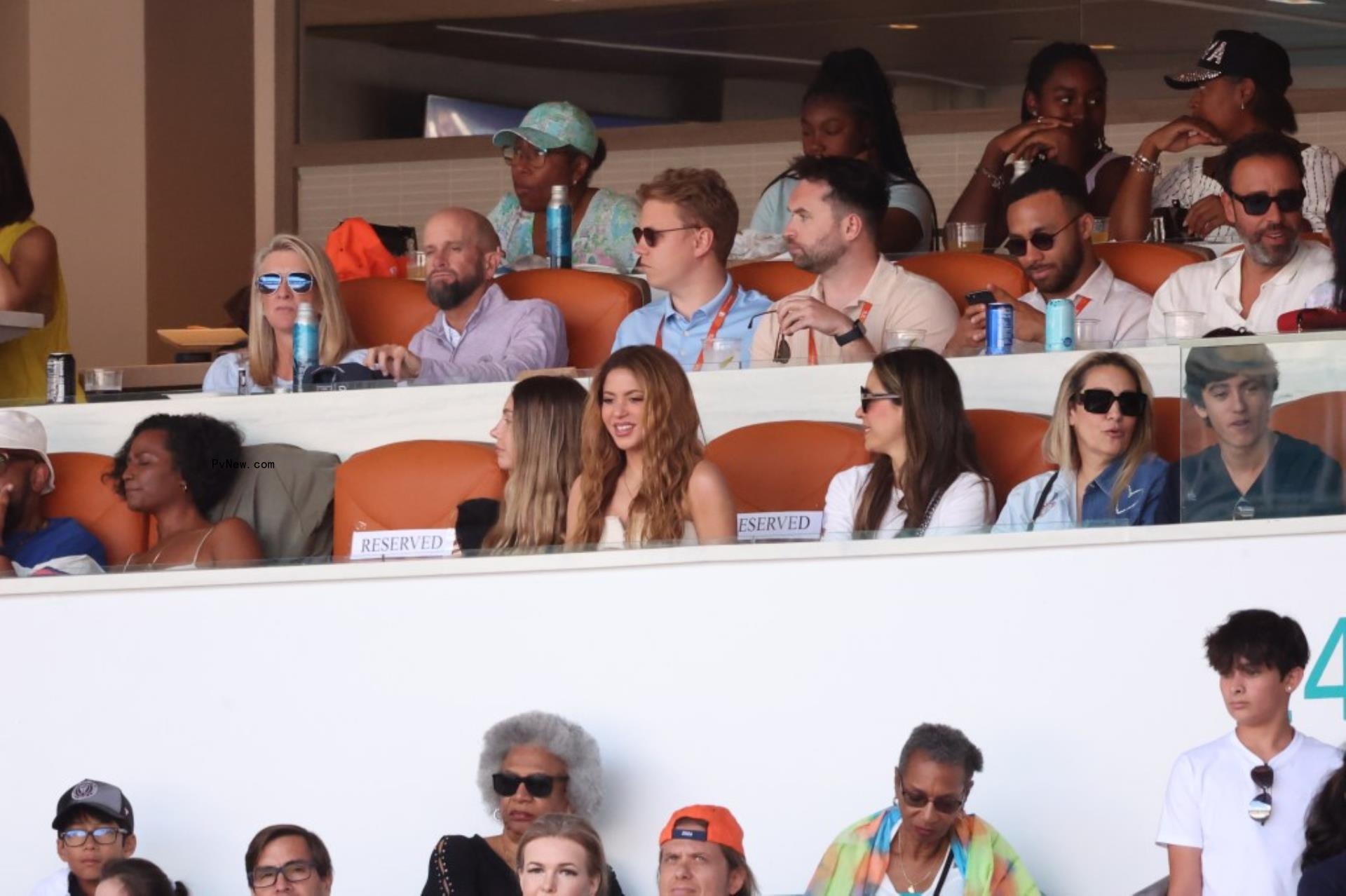 A group of people in a VIP box watching a sports event.