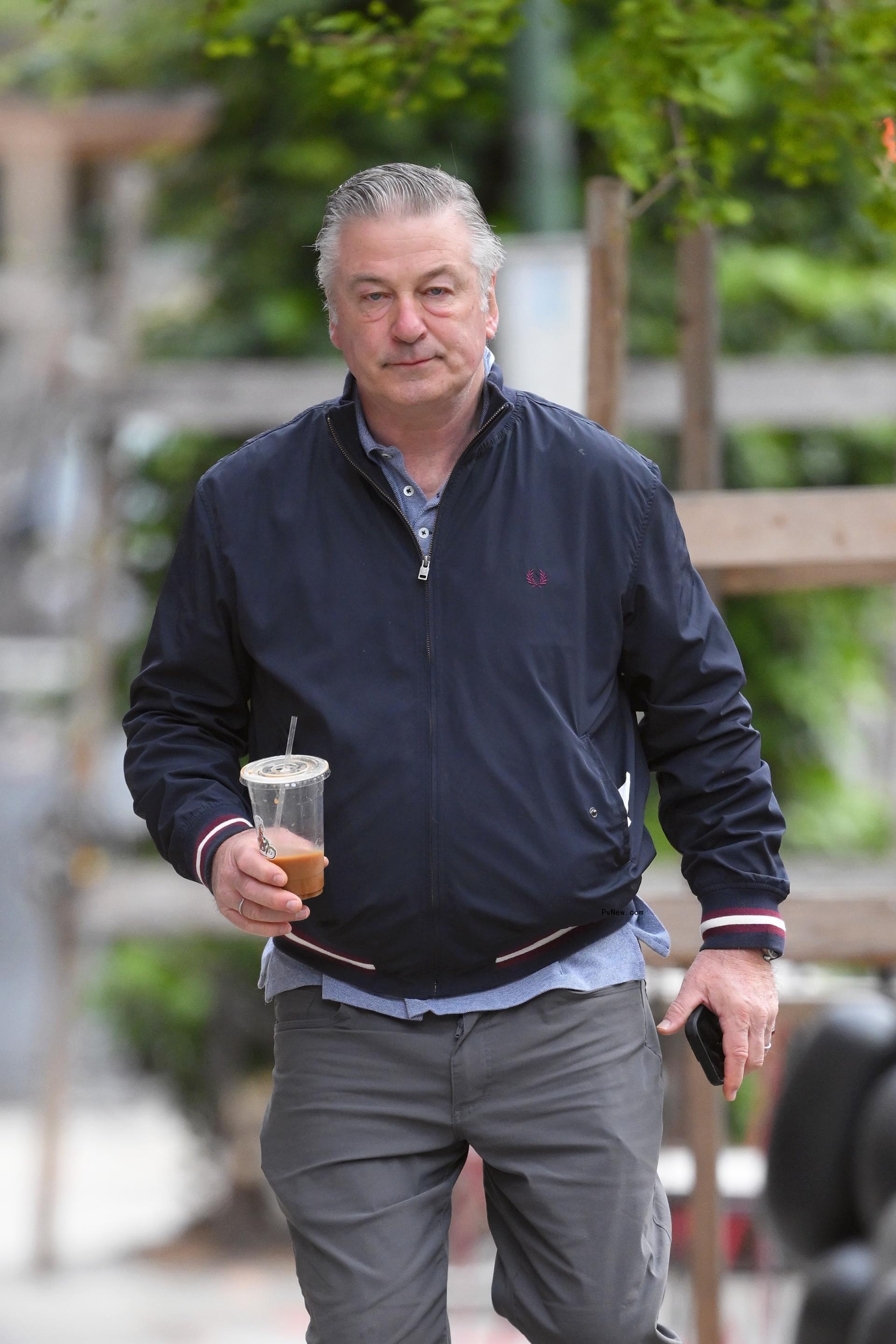 Alec Baldwin carrying a coffee.