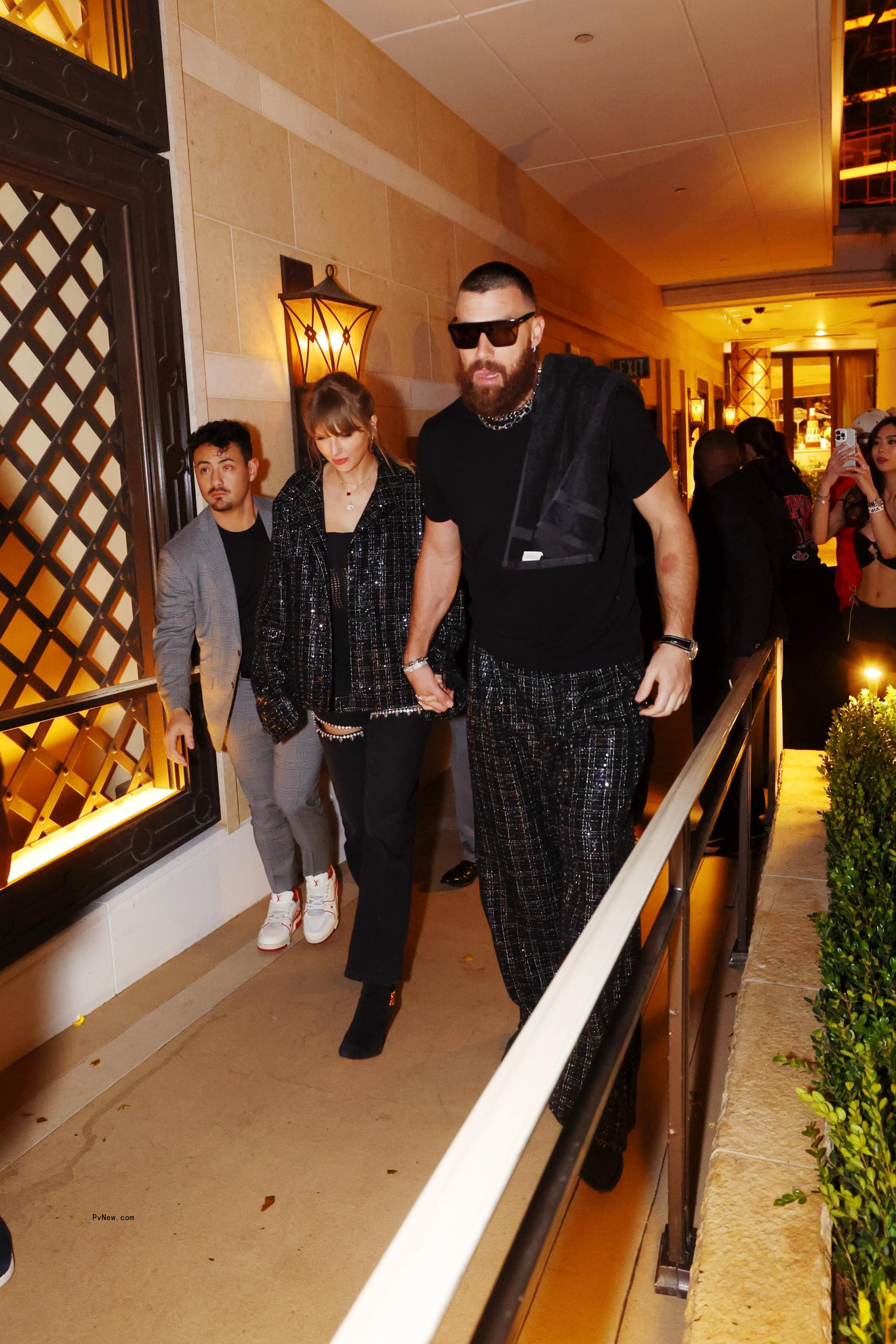 Taylor Swift and Travis Kelce holding hands.