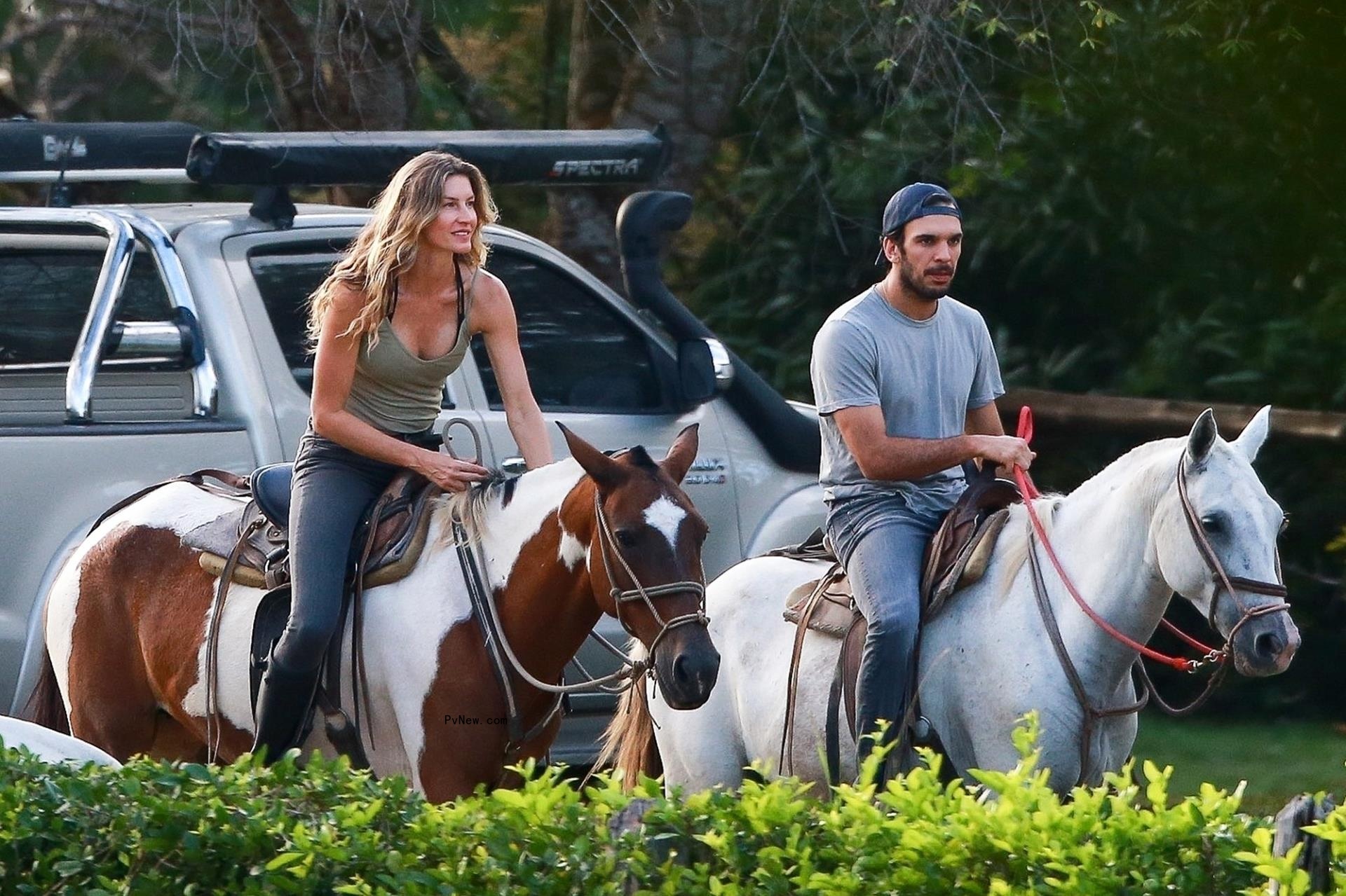 Gisele Bündchen's and Joaquim Valente on horseback with a car behind them.