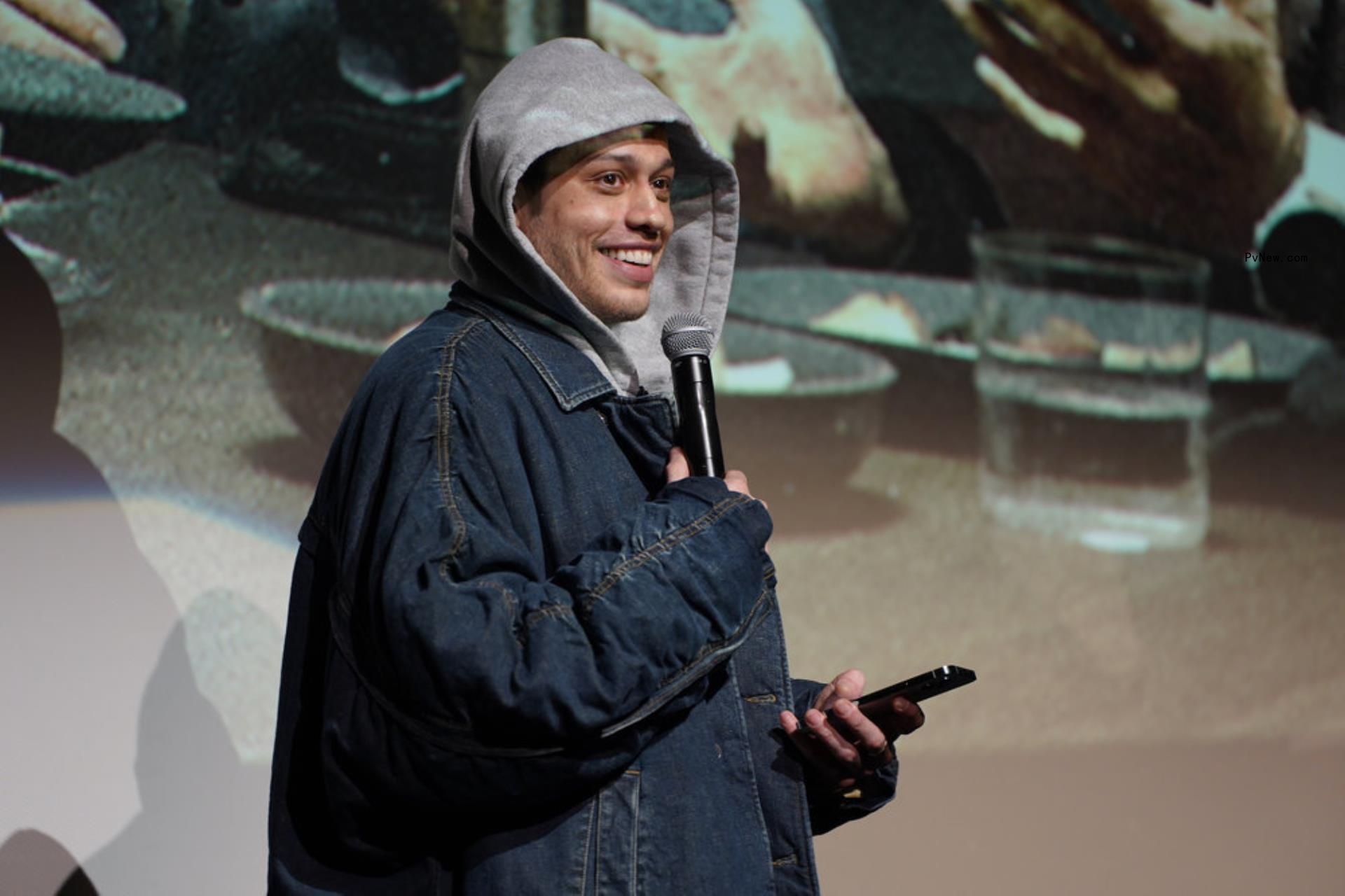 pete davidson with a mic and phone