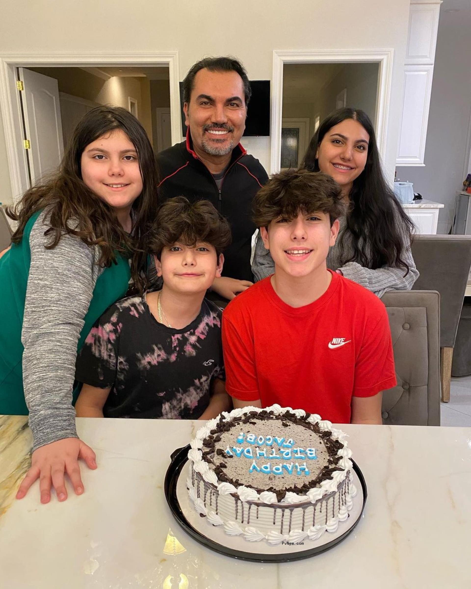 Bill Aydin posing with his kids in front of a birthday cake.