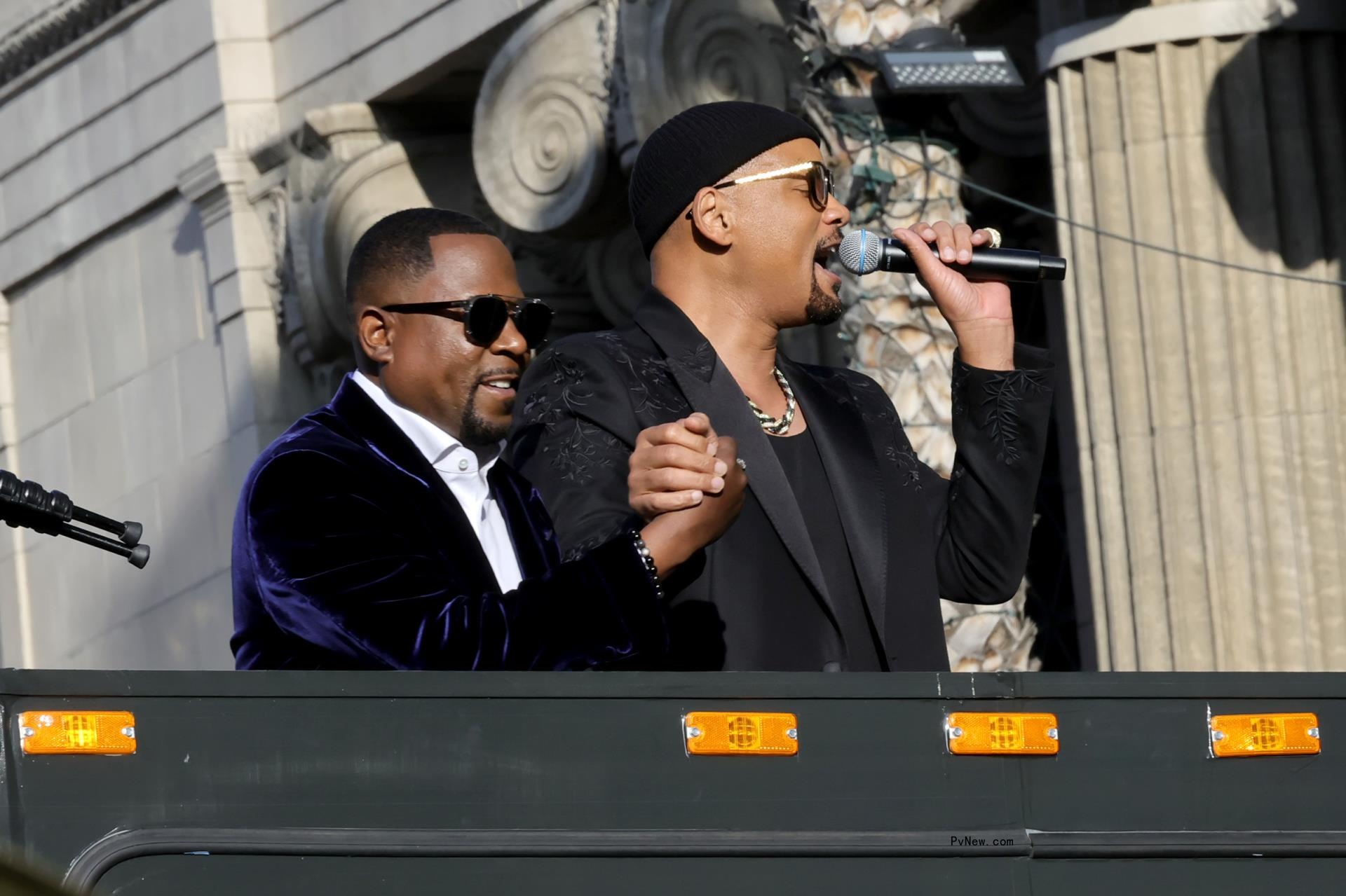 will smith holding martin lawrence's hand atop a bus
