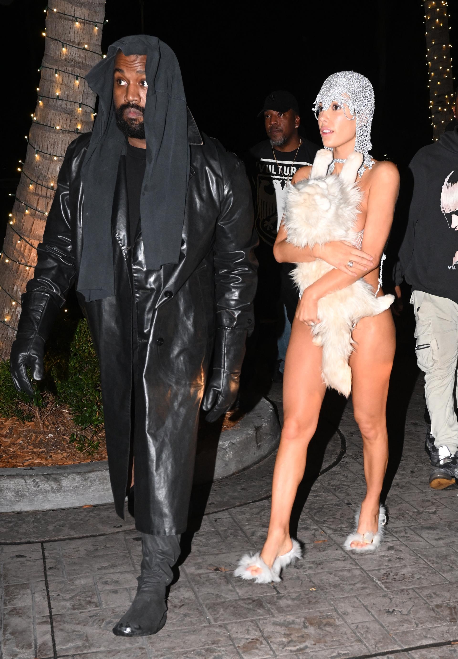Bianca Censor covers her modesty with a stuffed cat as she walks with Kanye West.