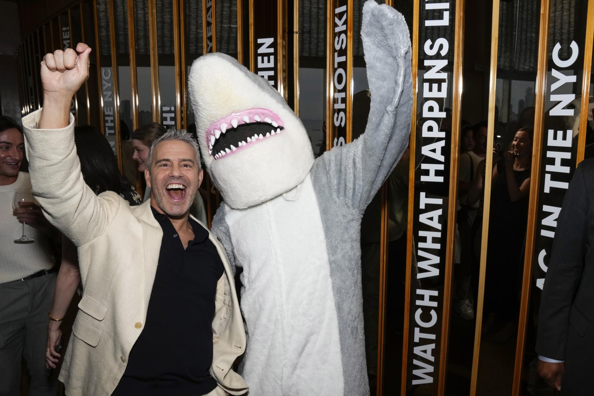 Andy Cohen posing with a shark mascot
