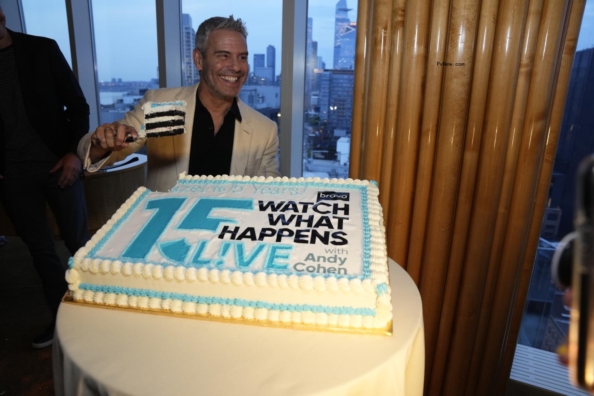 Andy Cohen posing with an anniversary cake