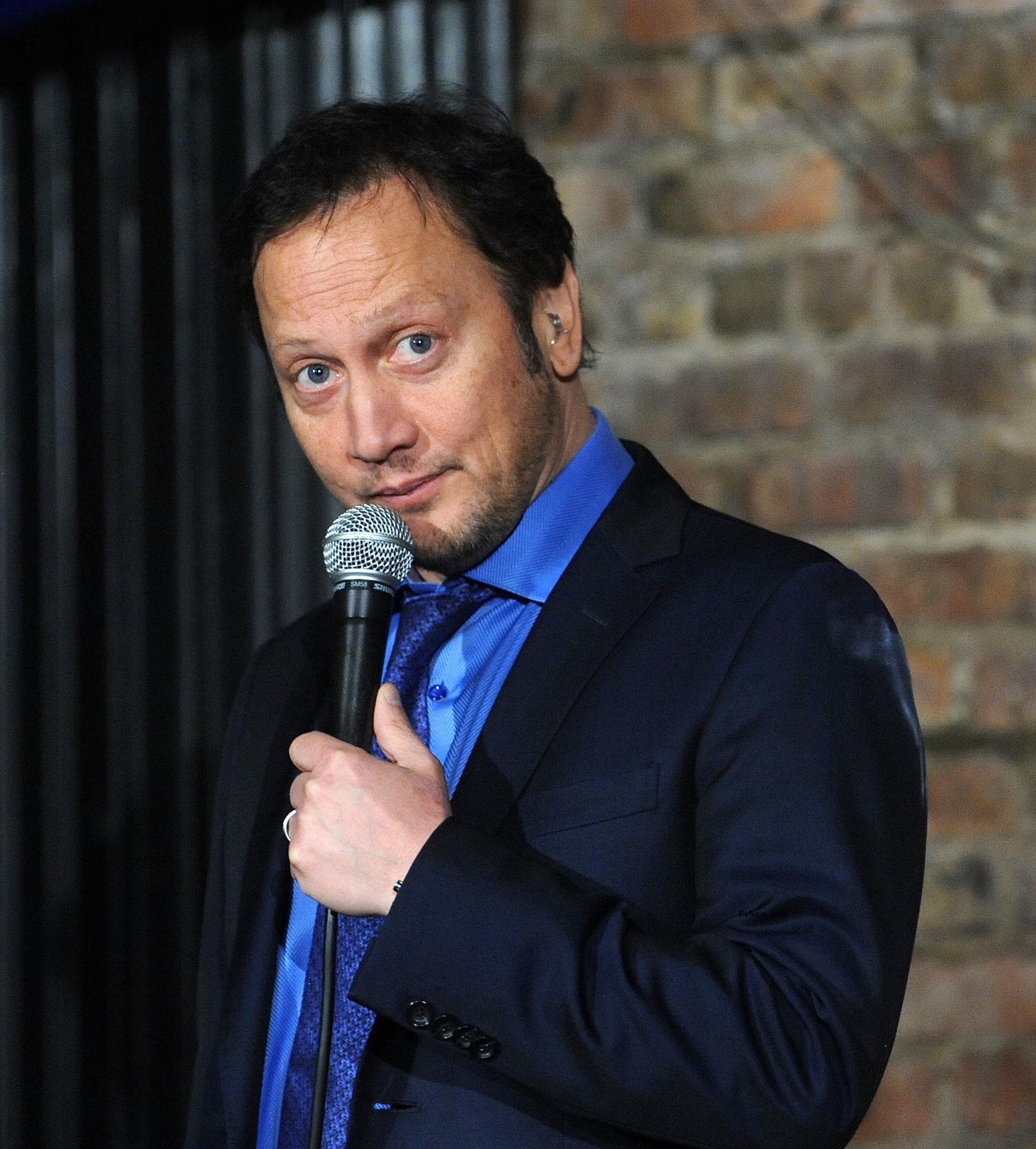 Rob Schneider holding a microphone.