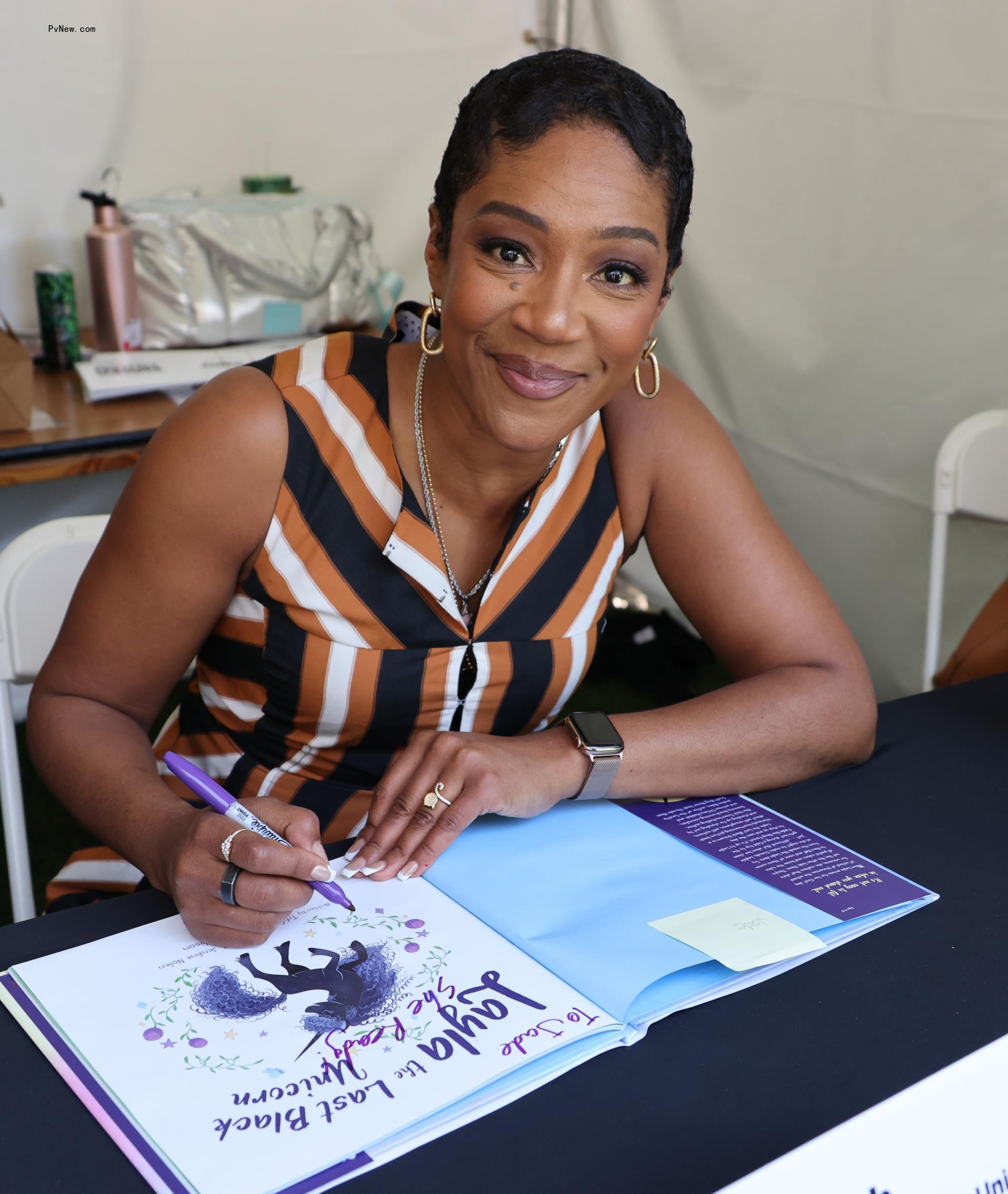 Tiffany Haddish signing a book. 