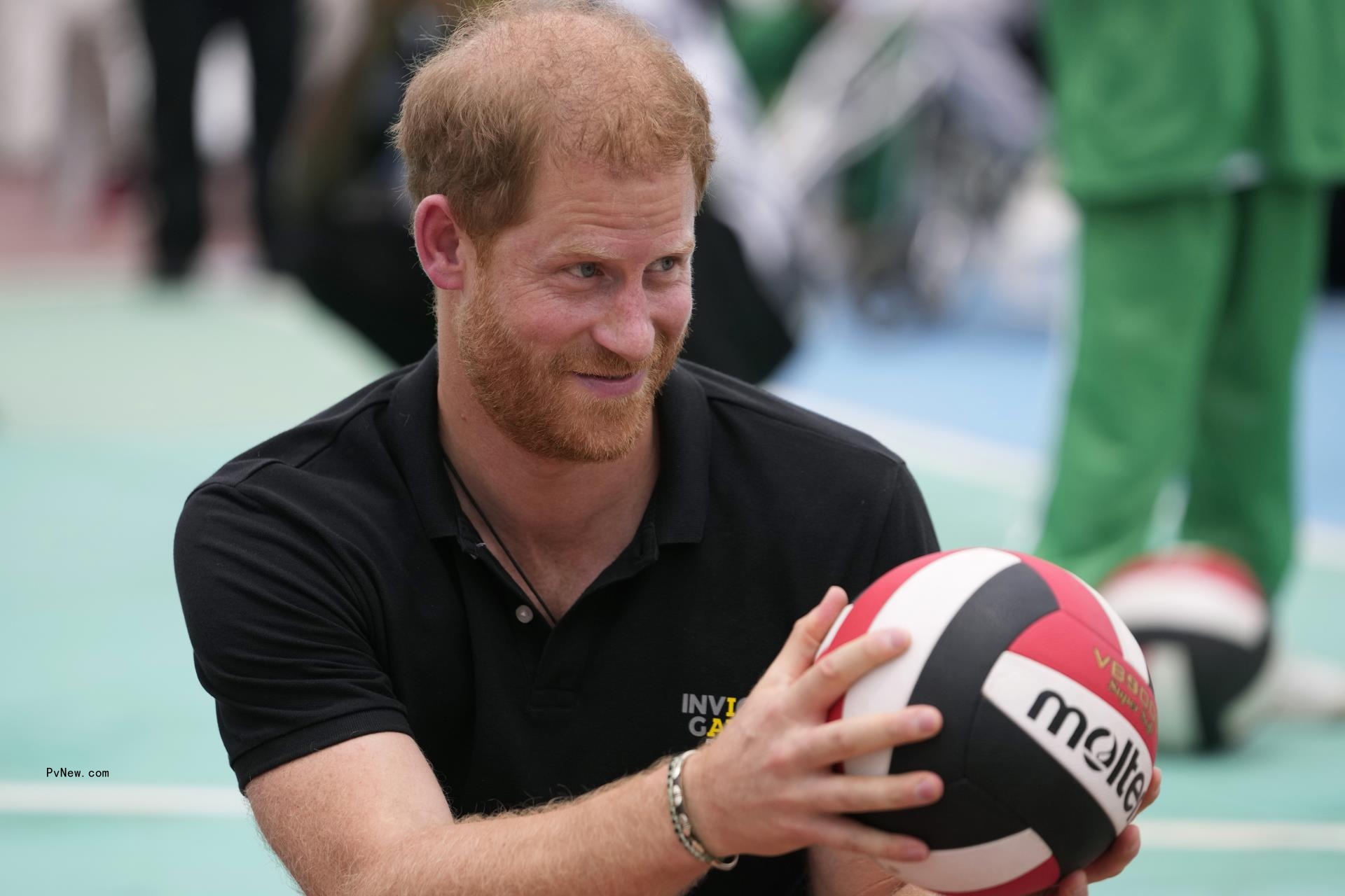 Prince Harry holding a volleyball.