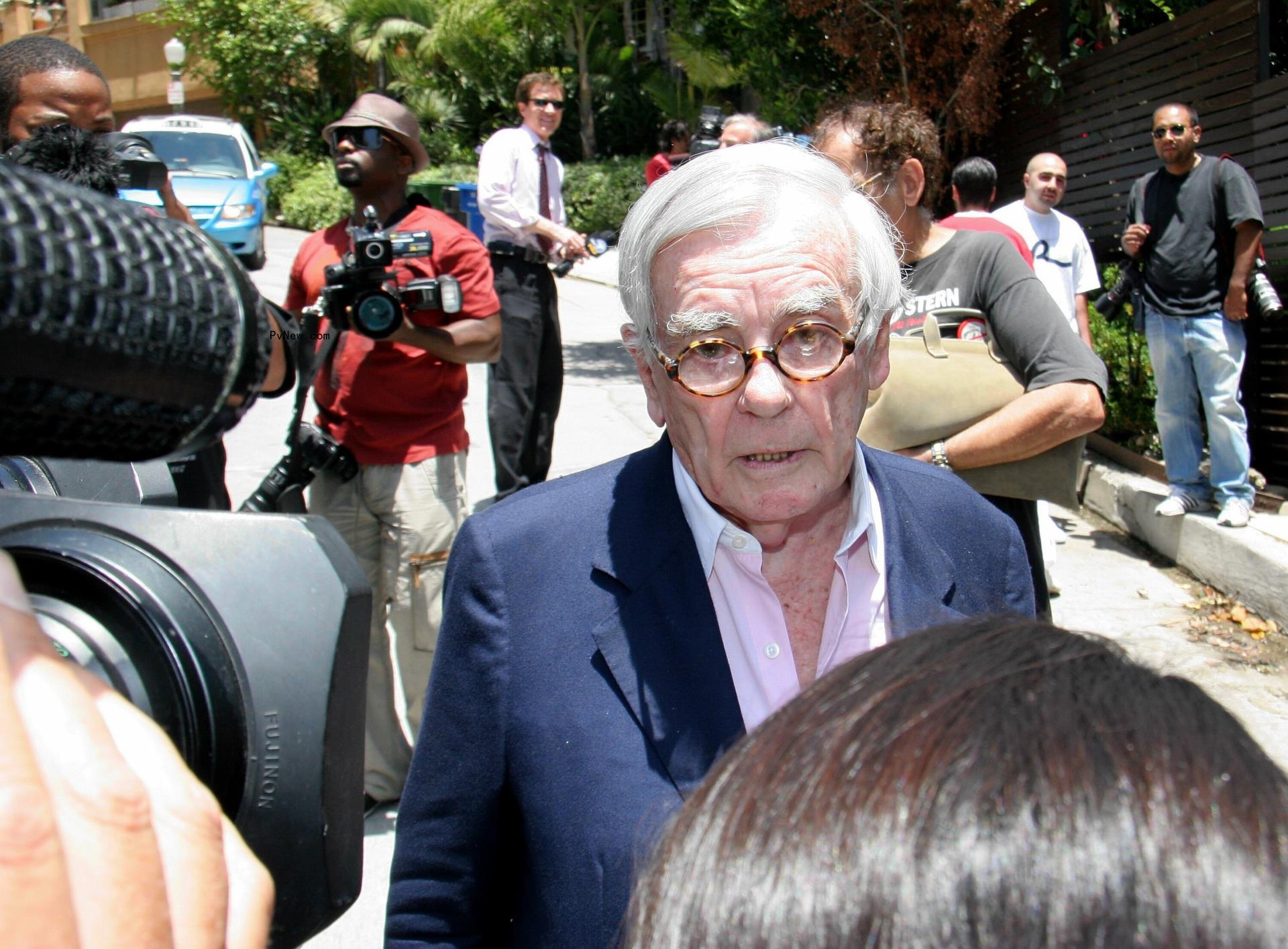 Dominick Dunne speaking with a reporter while a camera is pointed at him