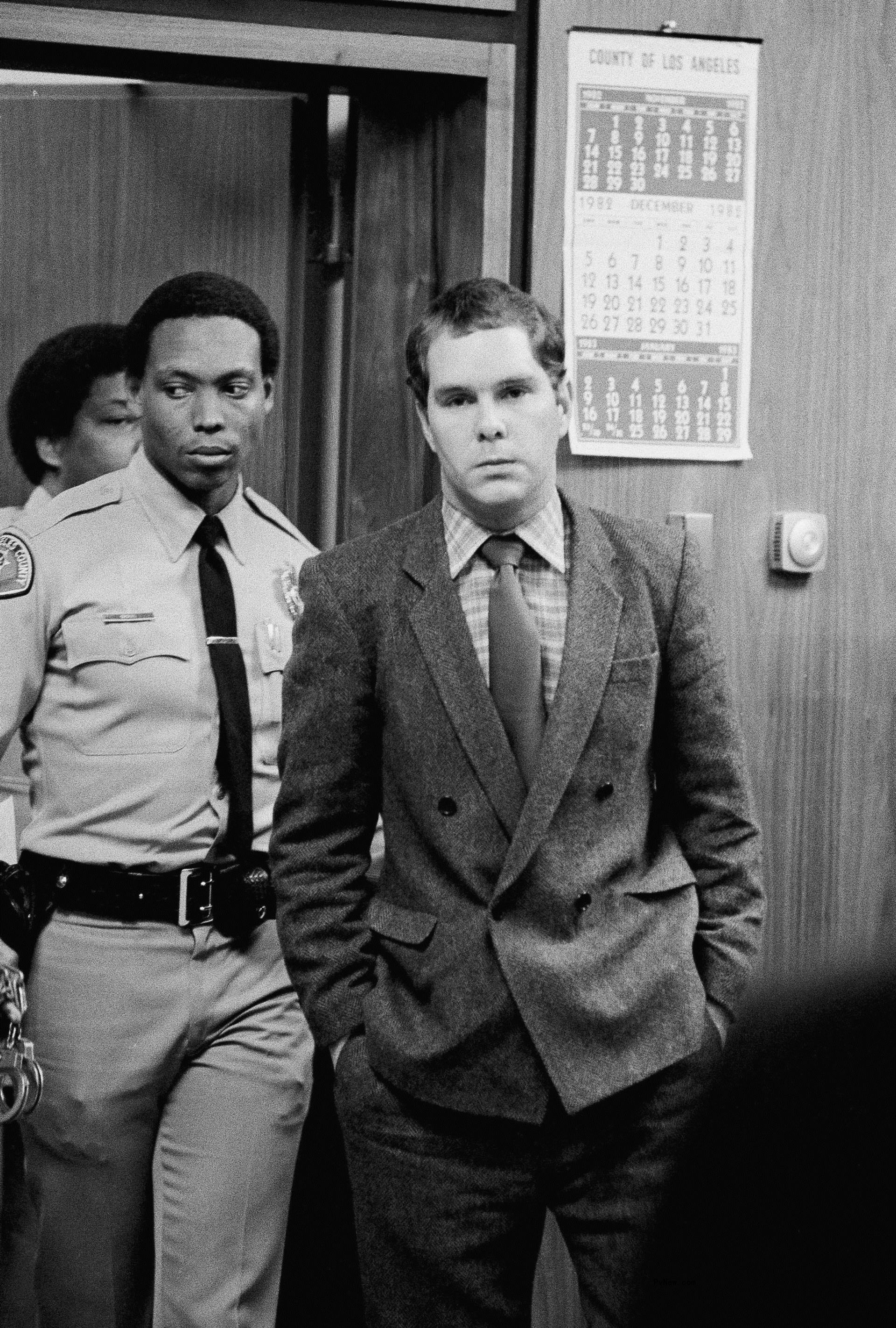 John Thomas Sweeney being led into court by a police officer.