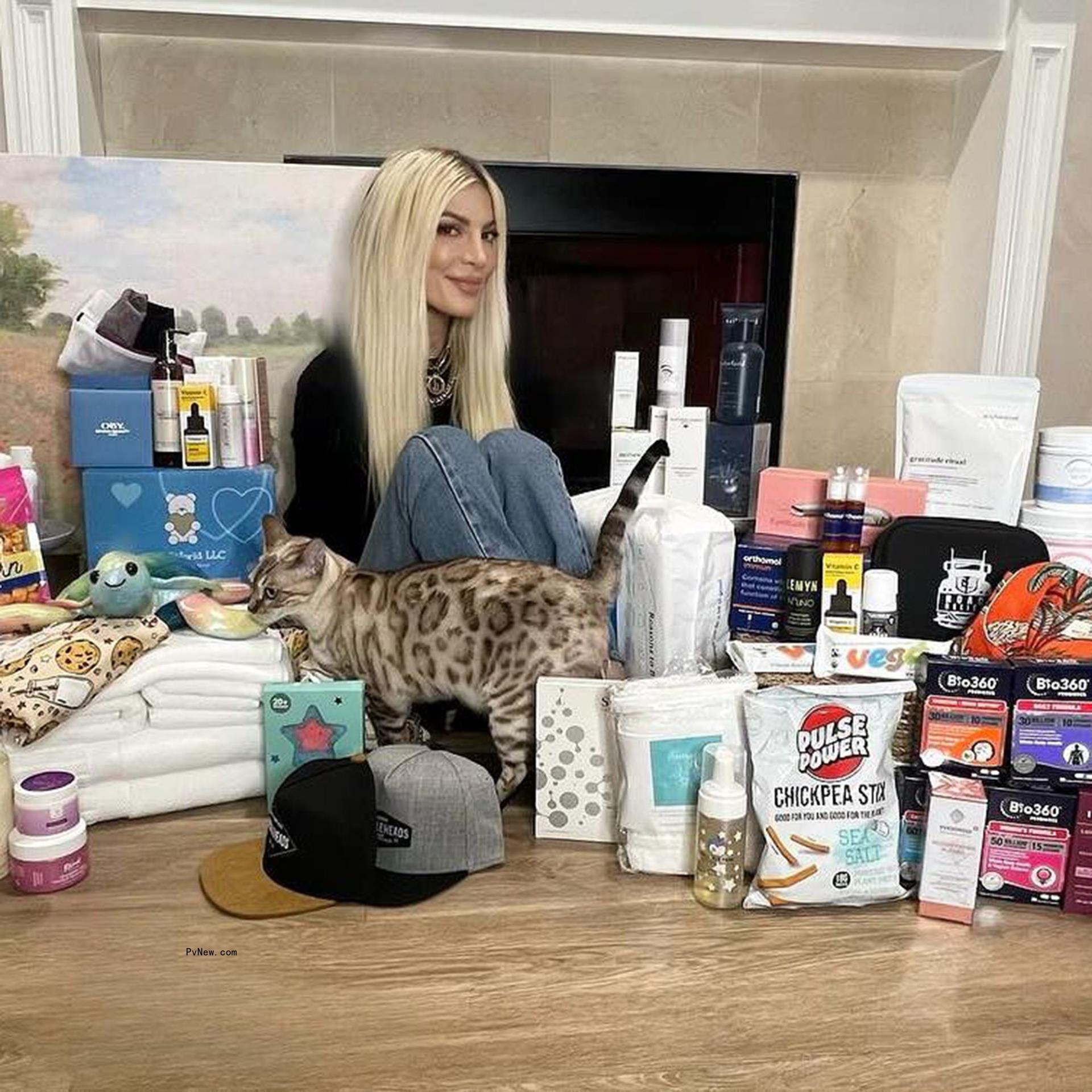 Tori Spelling sitting with household items on a table
