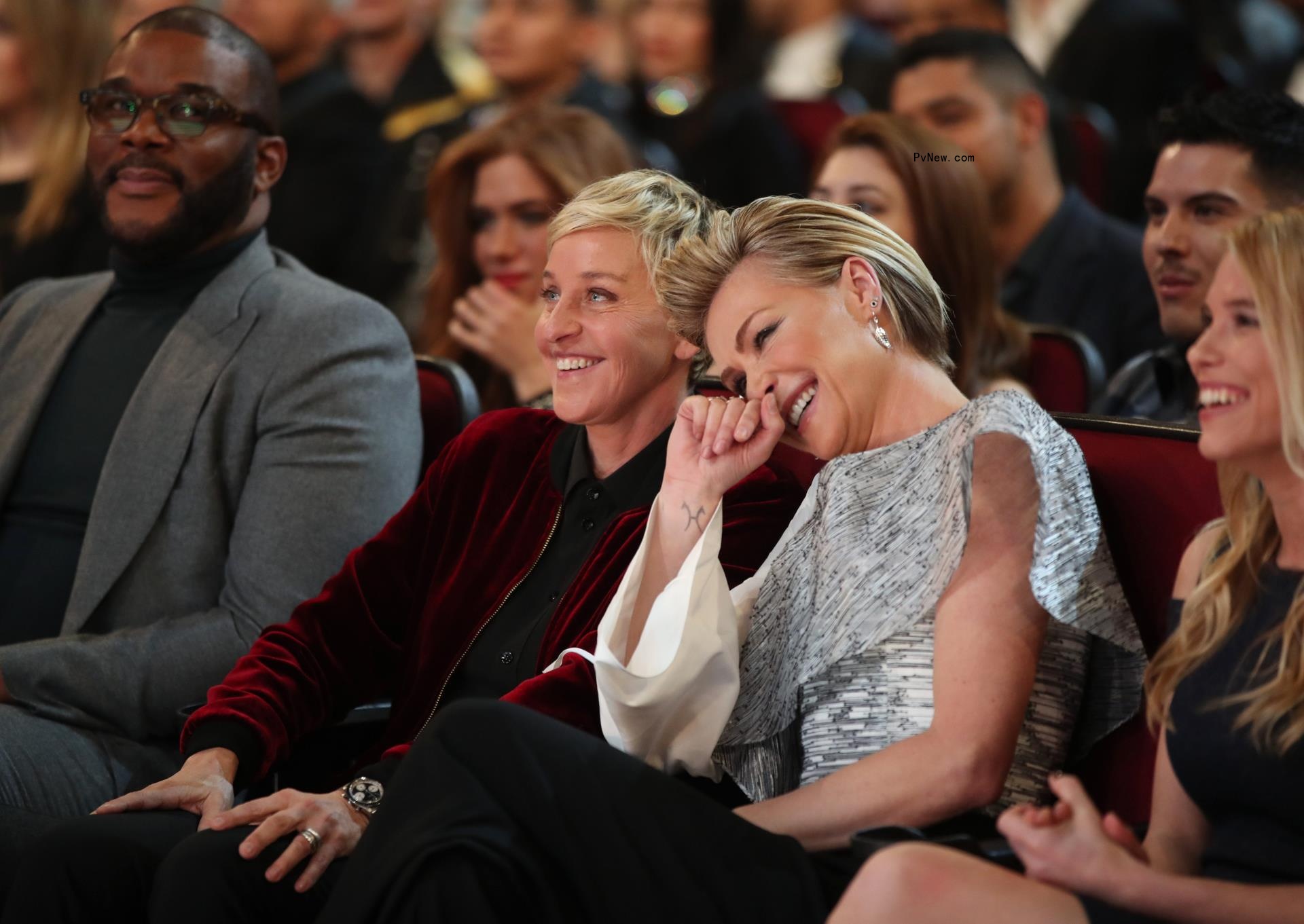 Ellen DeGeneres and Portia De Rossi seated and laughing at the 2017 People's Choice Awards.