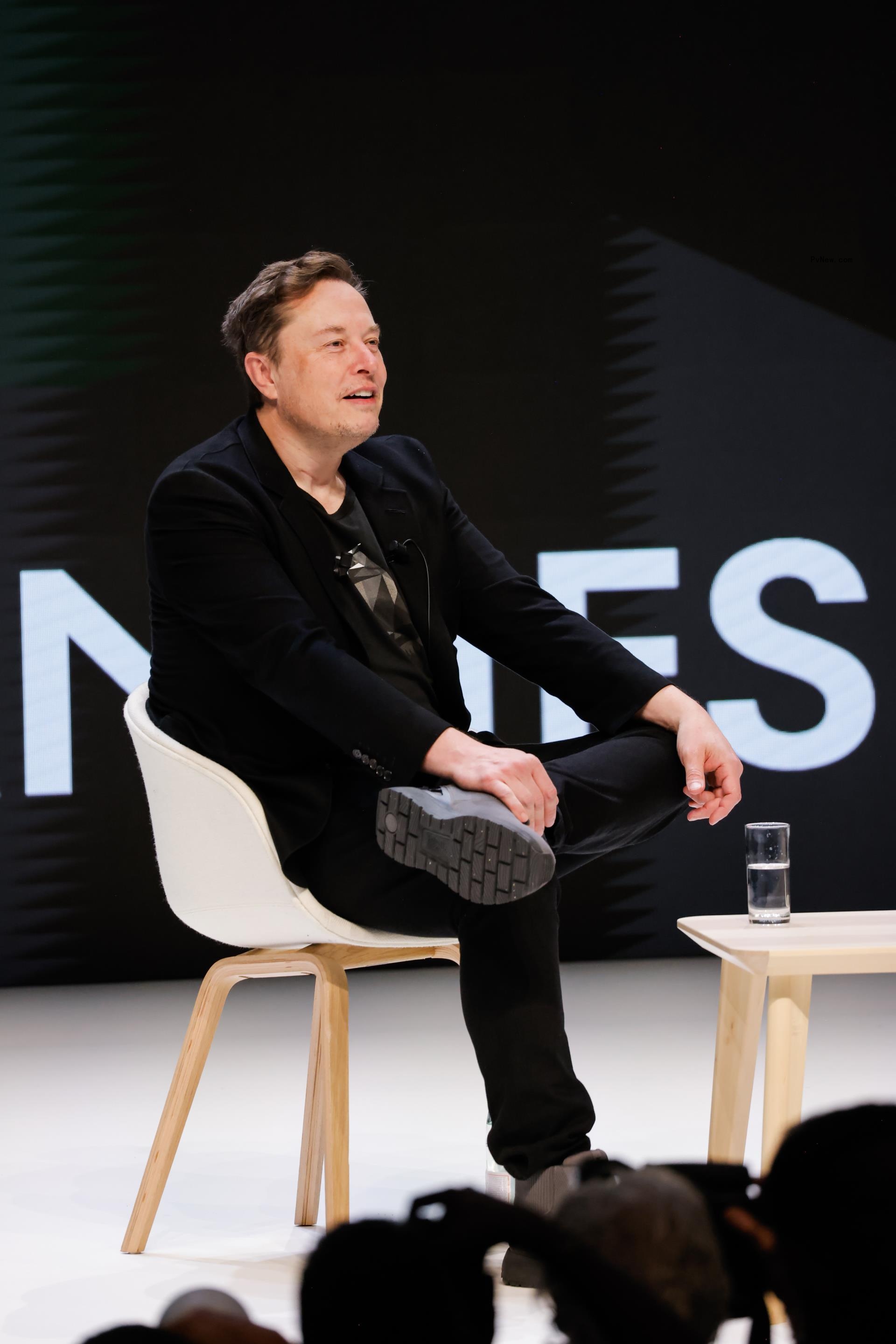elon musk sitting on a stage