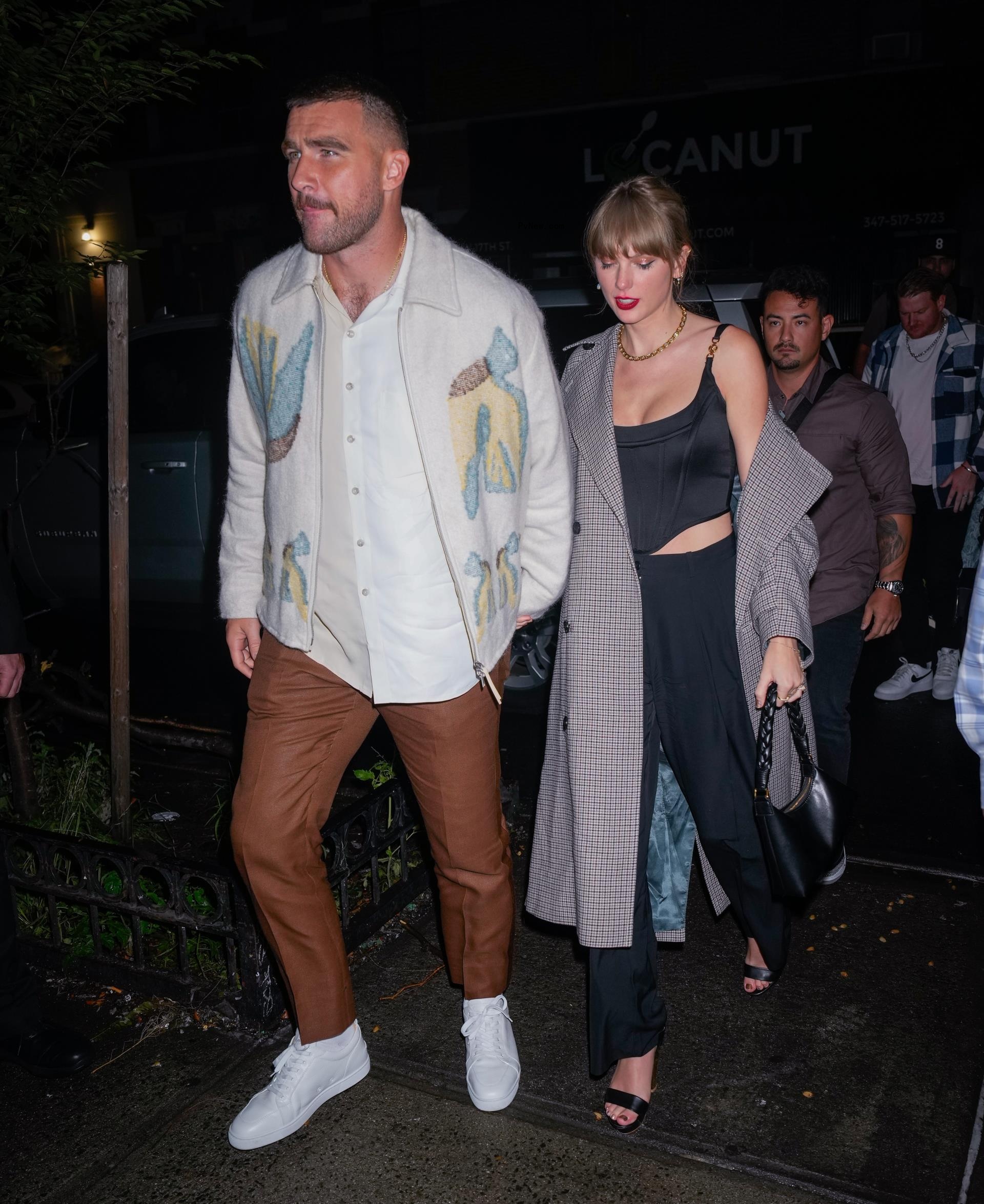 Travis Kelce and Taylor Swift holding hands.