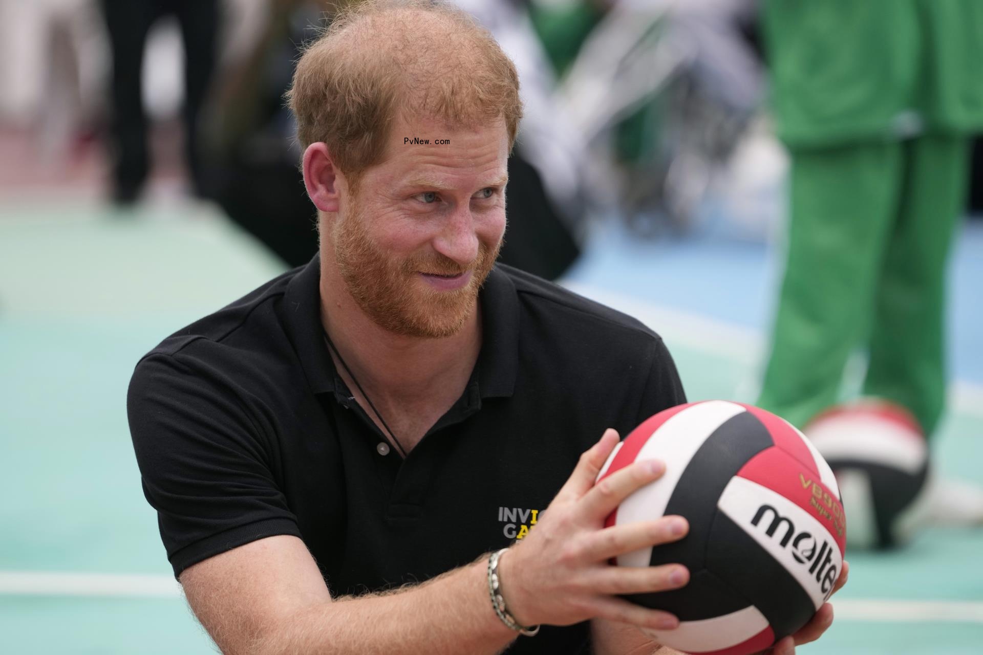 Prince Harry holding a volleyball.