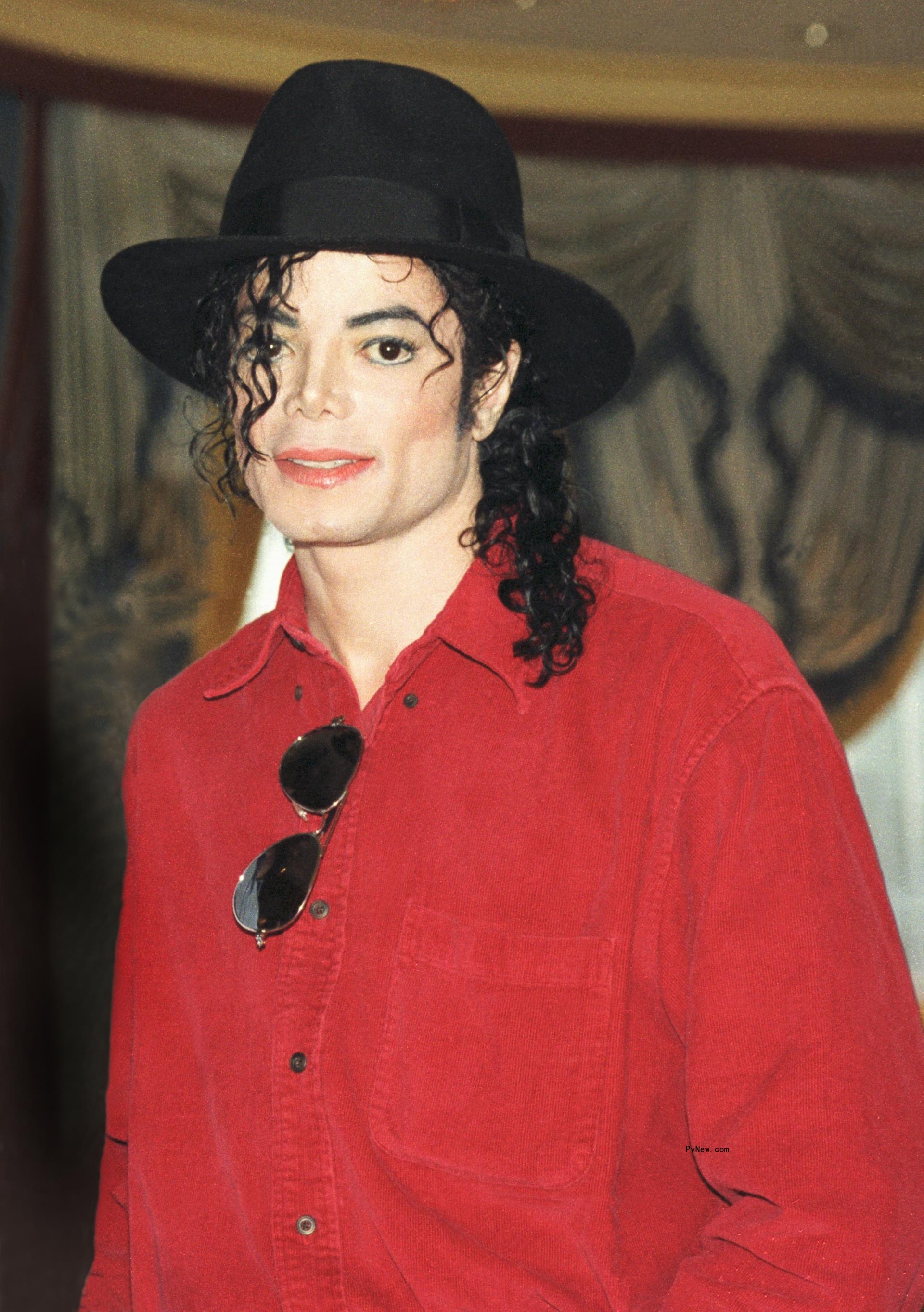 Michael Jackson in a red shirt and black hat in 1996.