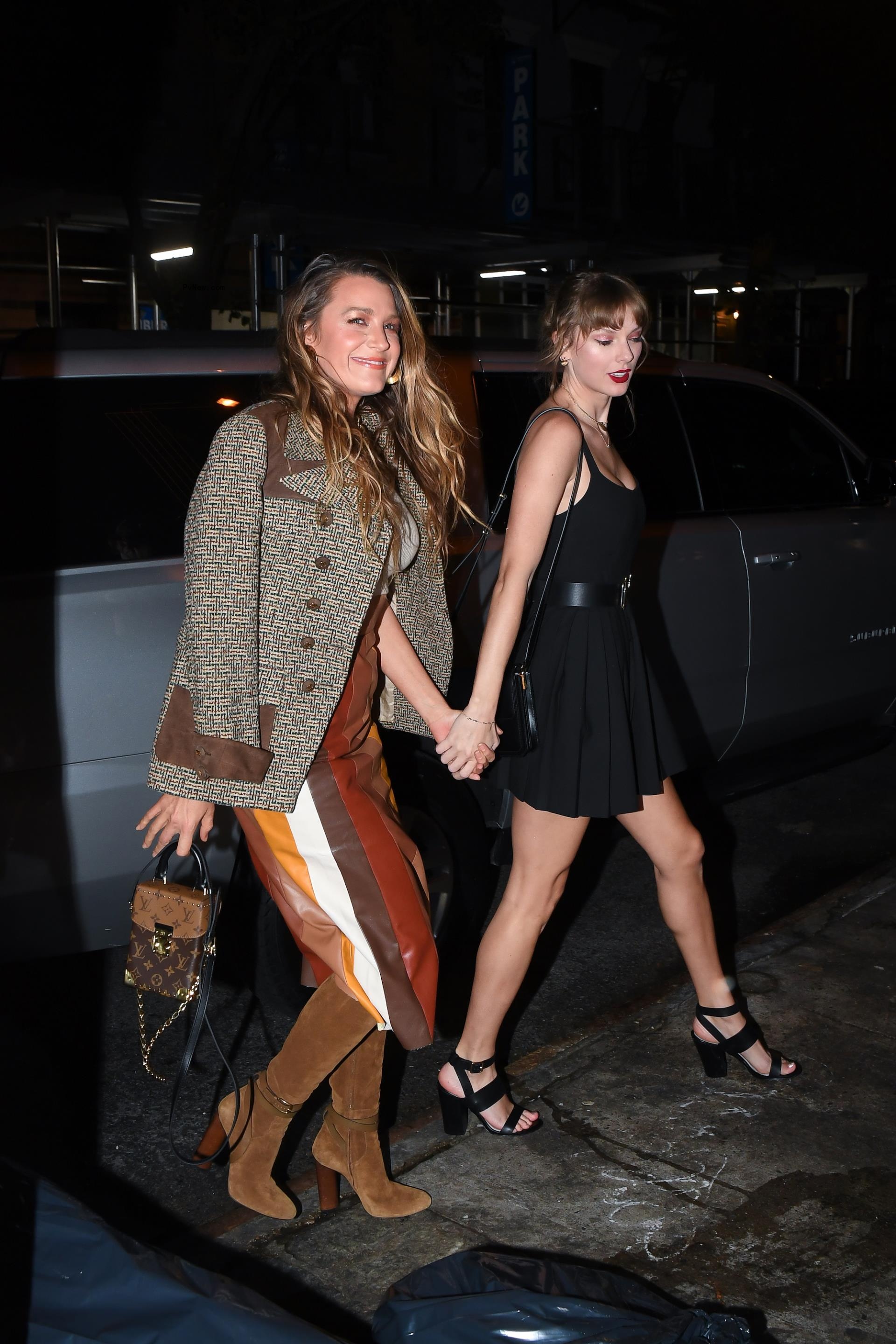 Blake Lively and Taylor Swift holding hands.
