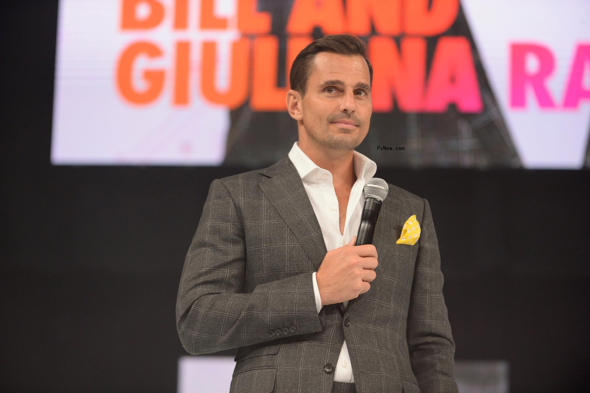 bill rancic holding a microphone on stage