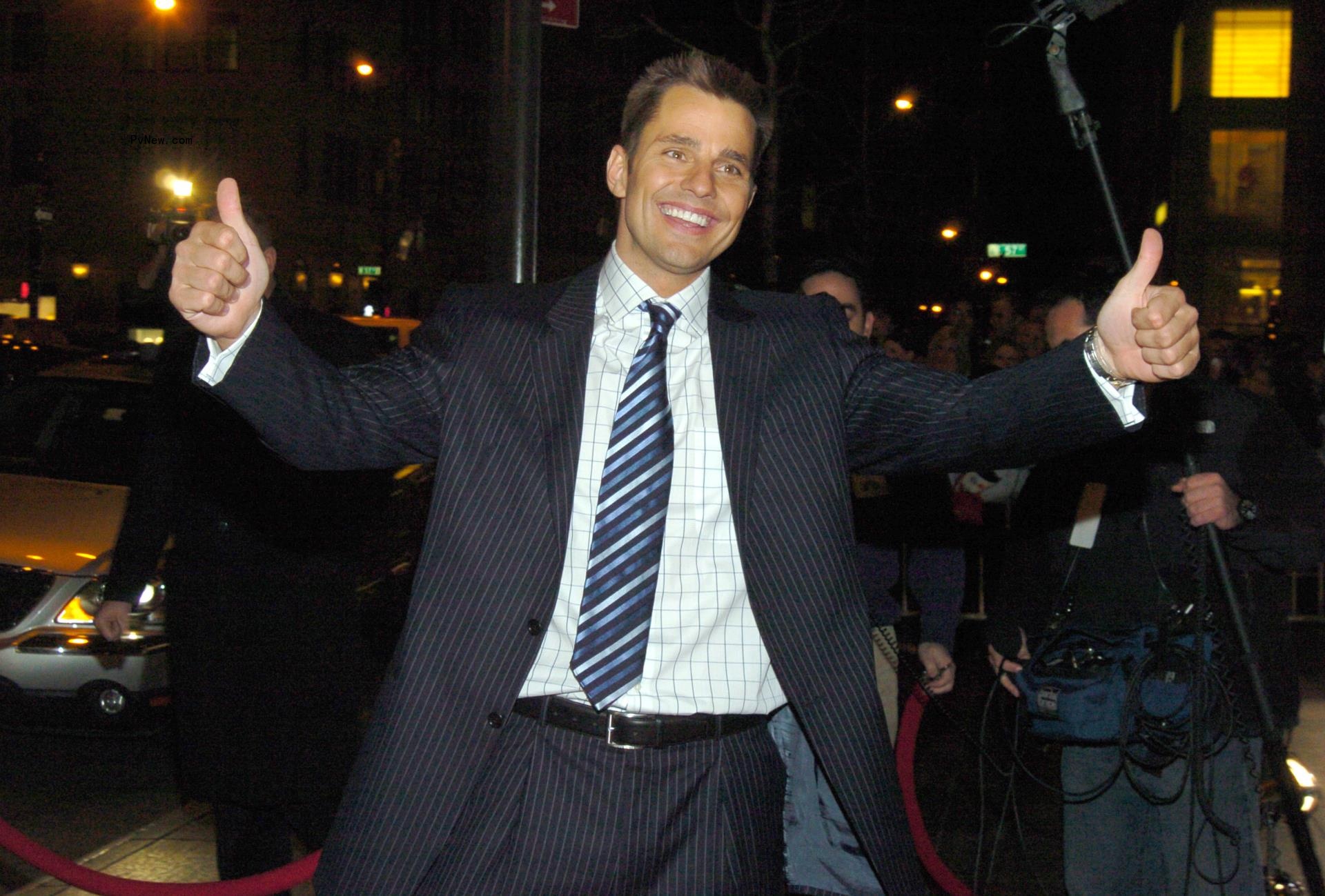 bill rancic with his arms wide in celebration