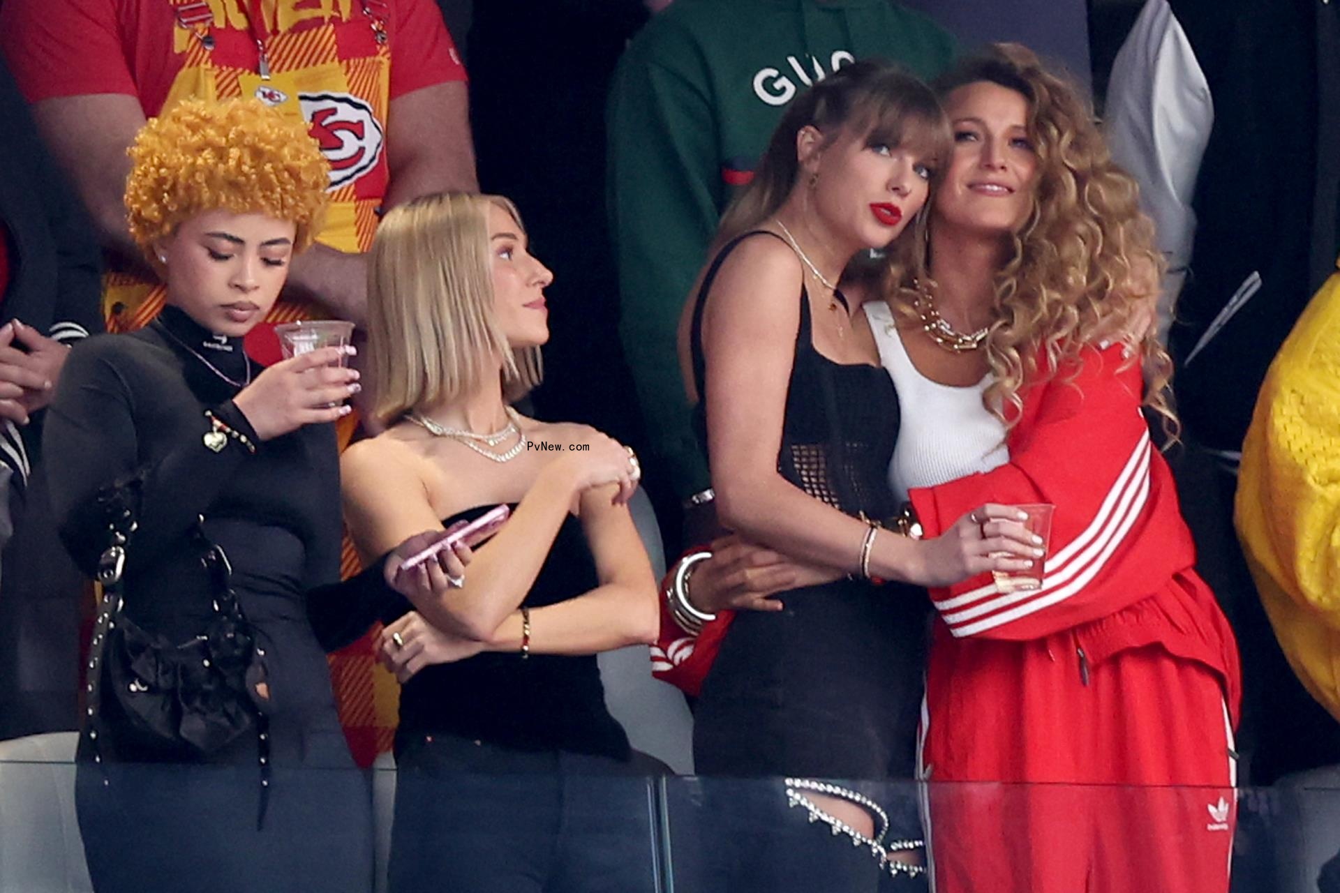 Ice Spice holds a drink while Taylor Swift hugs Blake Lively at the 2024 Super Bowl.