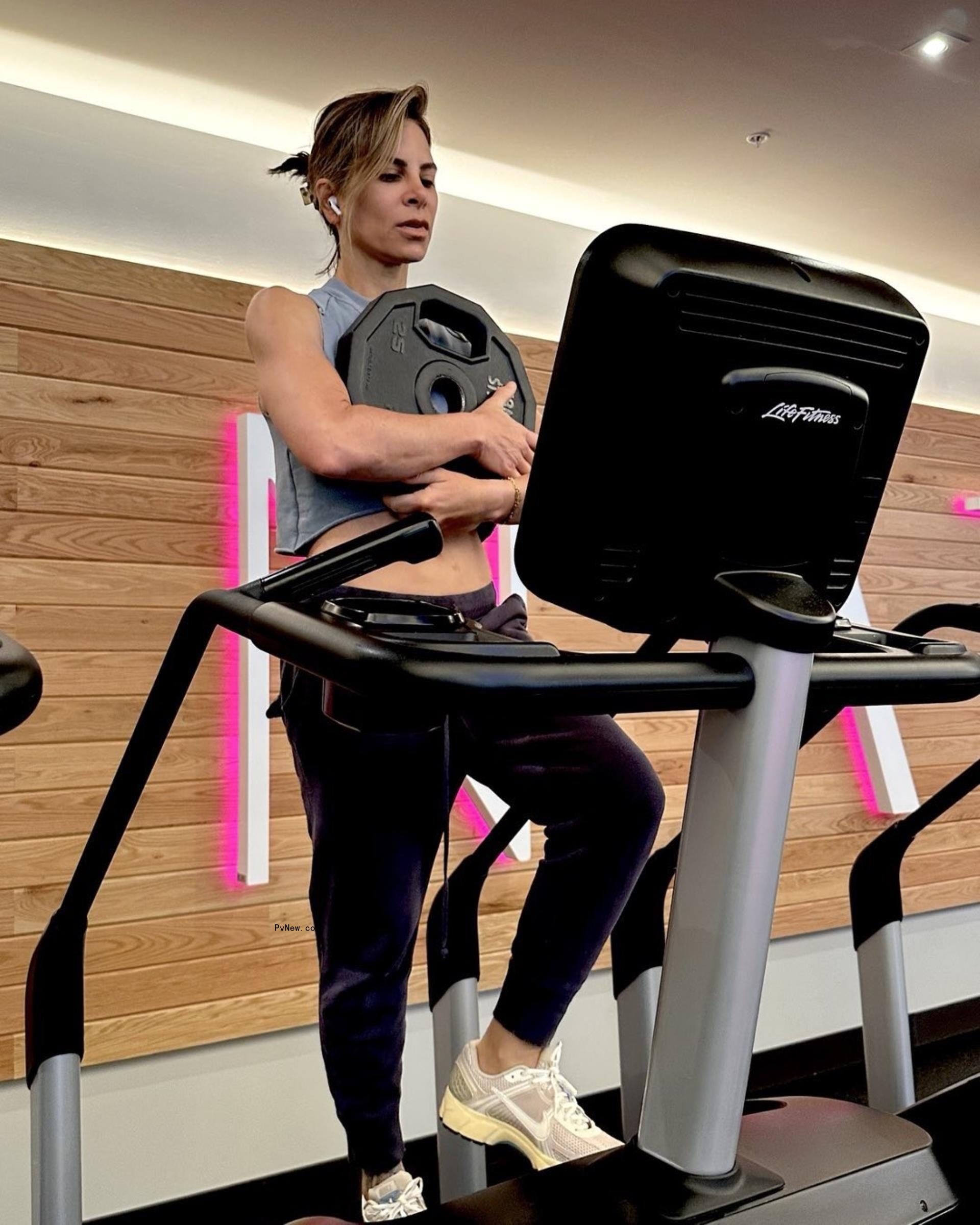 jillian michaels walking on a stairmaster holding a weighted plate