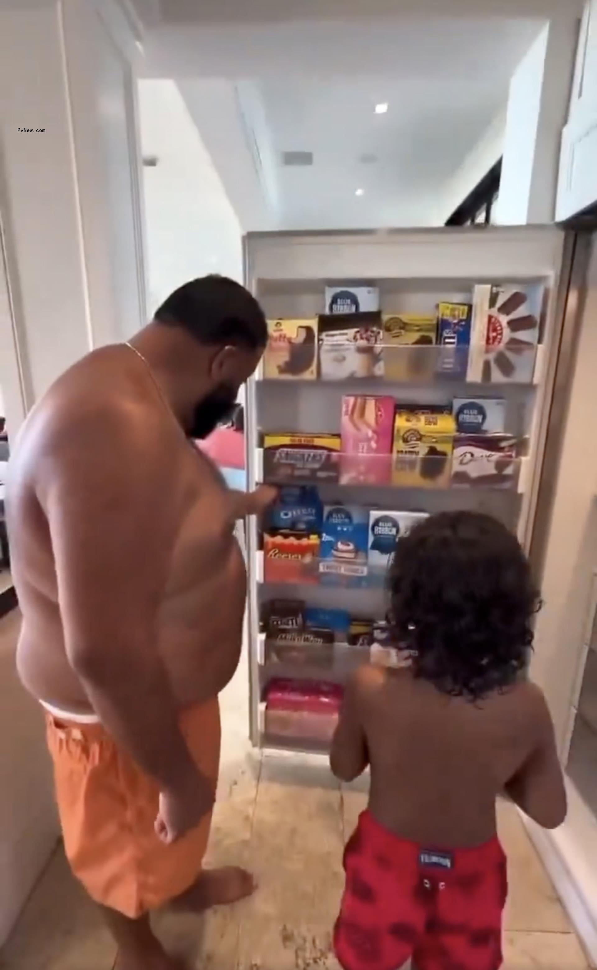 DJ Khaled and his son looking at his ice cream-filled refrigerator.