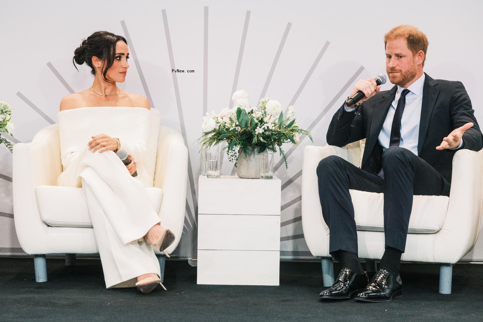 Prince Harry speaks as his wife, Meghan Markle, looks on.