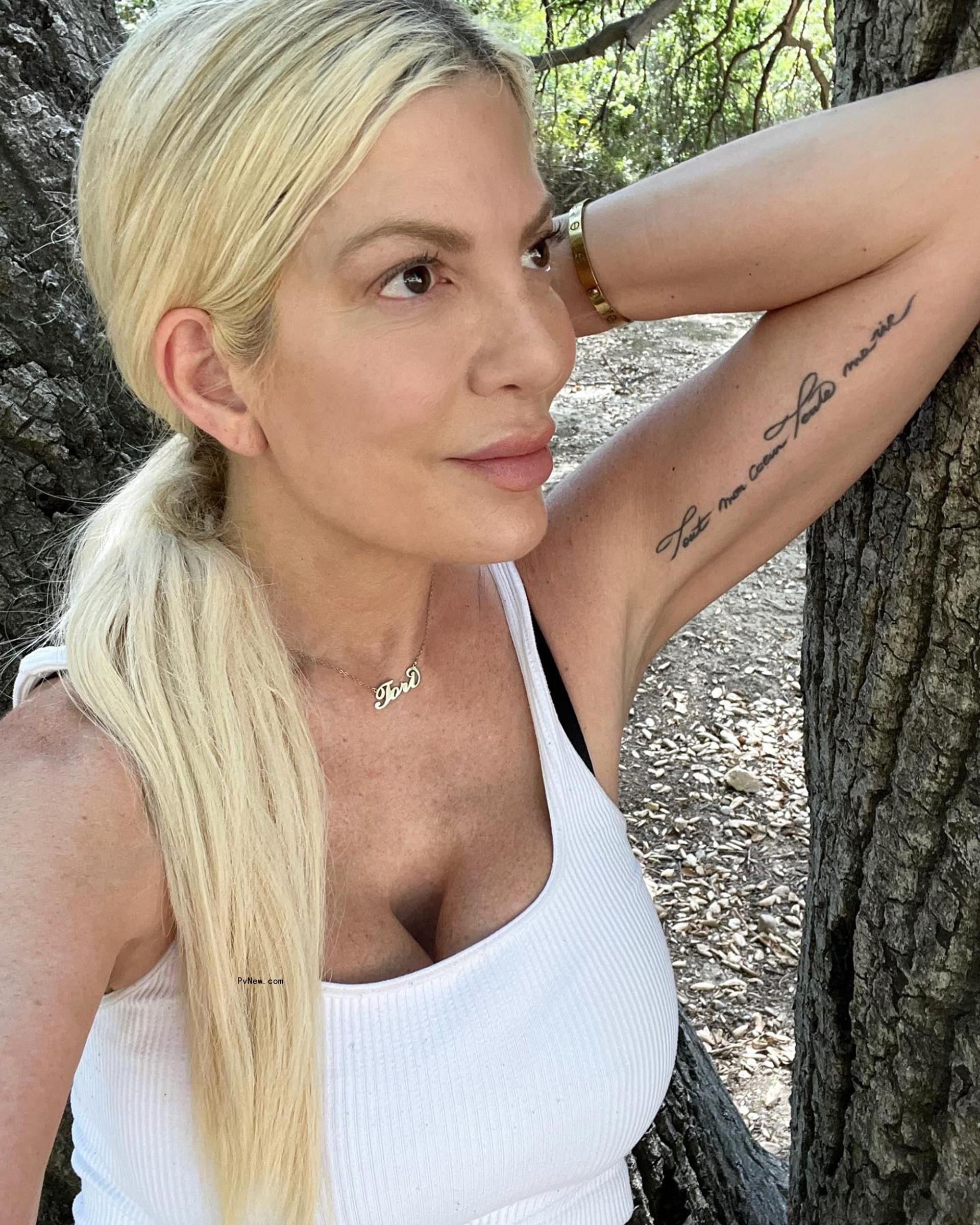 Tori Spelling posing near a tree