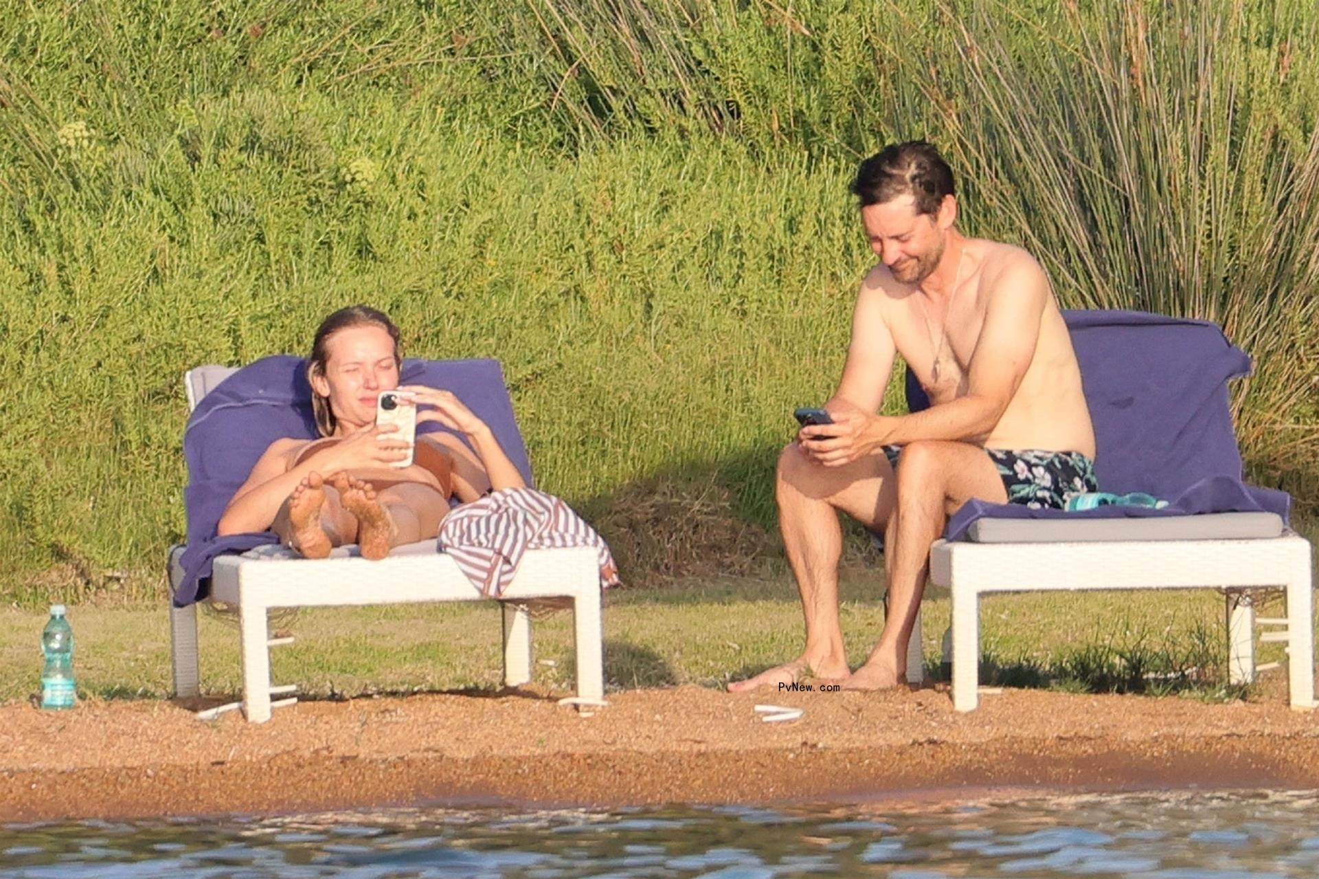 Babette Strijbos and Tobey Maguire lying down on beach chairs.
