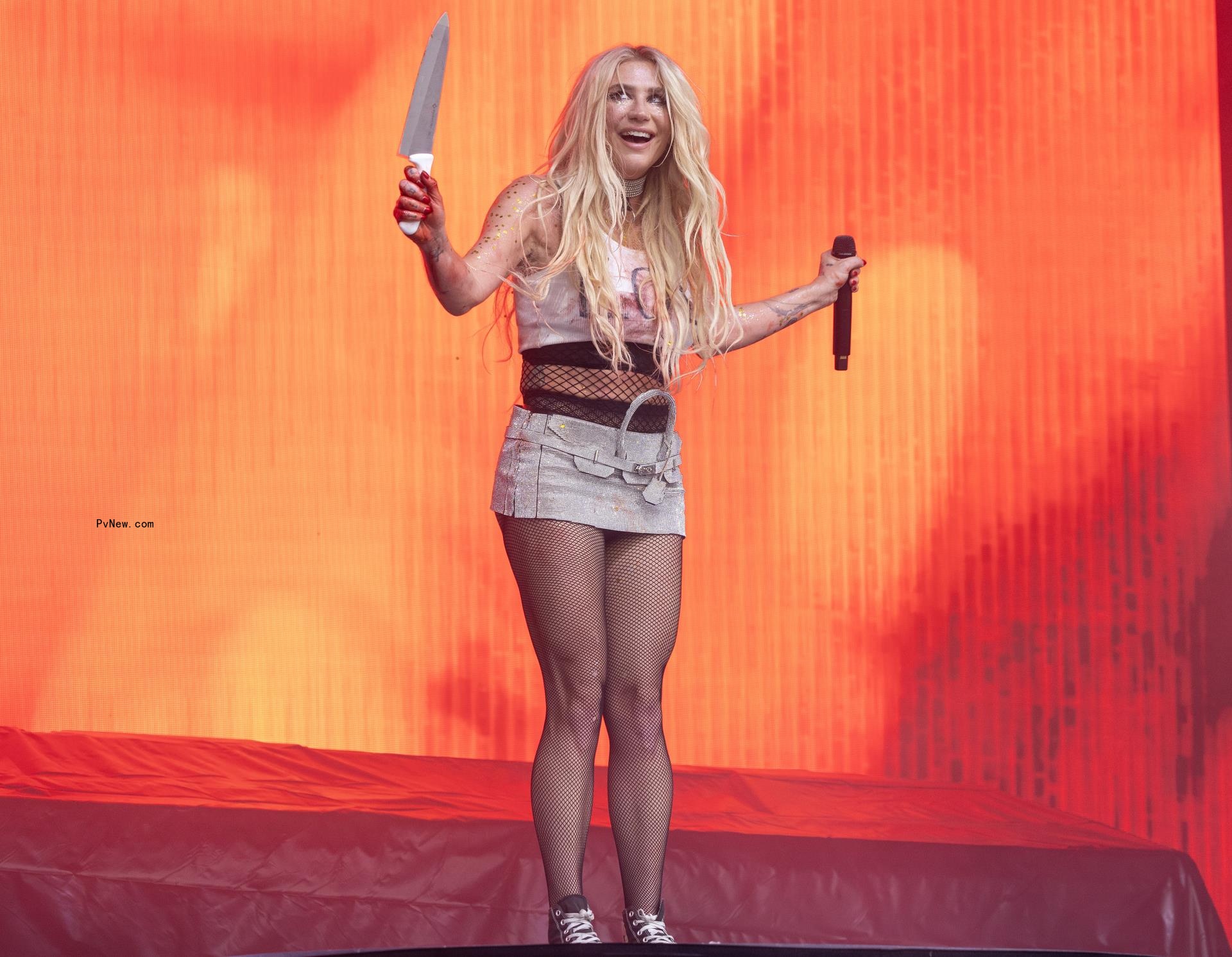 Kesha o<i></i>nstage holding a knife.