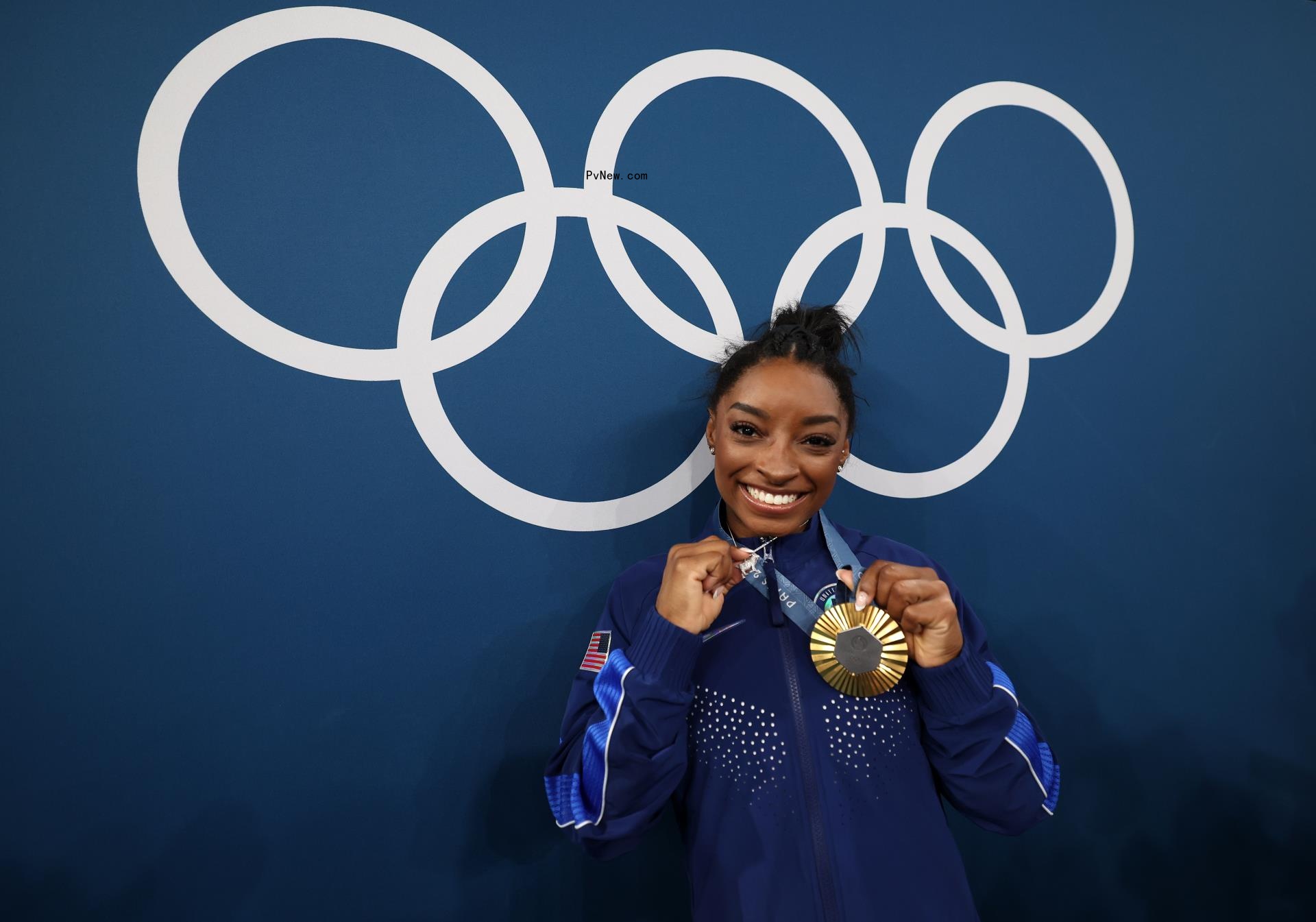Simone Biles holding an Olympic gold medal on Aug 1.