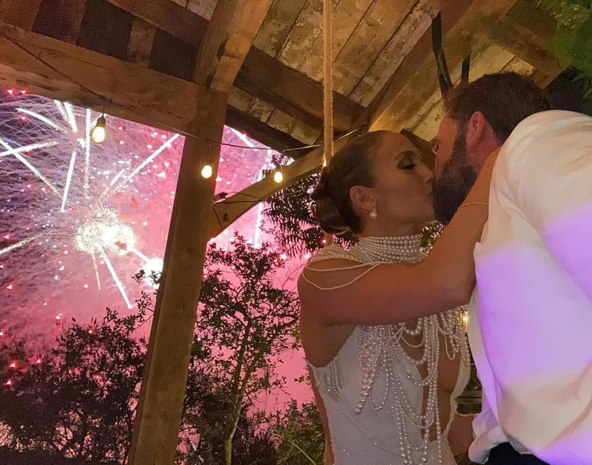 Jennifer Lopez and Ben Affleck kissing at wedding, with fireworks in the background