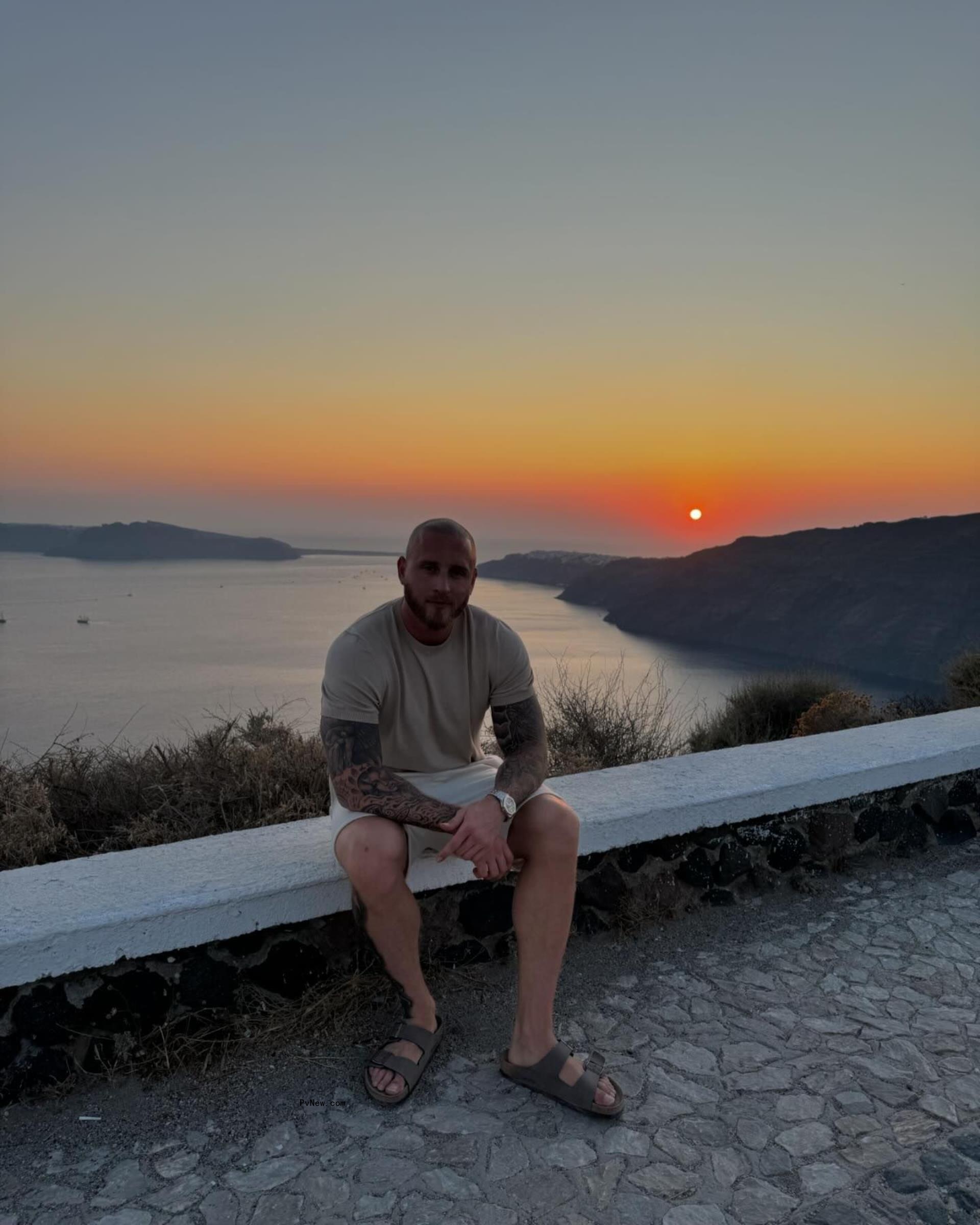 chet hanks sitting on a stone wall against a sunset