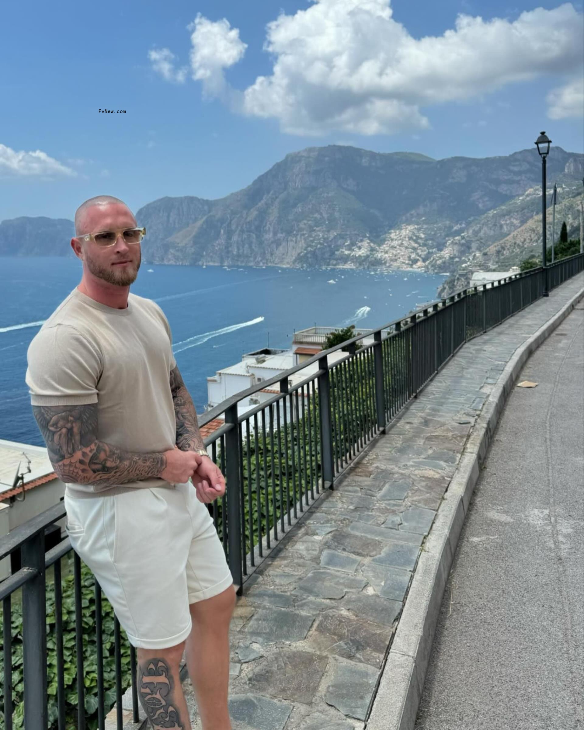 chet hanks leaning against a me<i></i>tal railing above the ocean