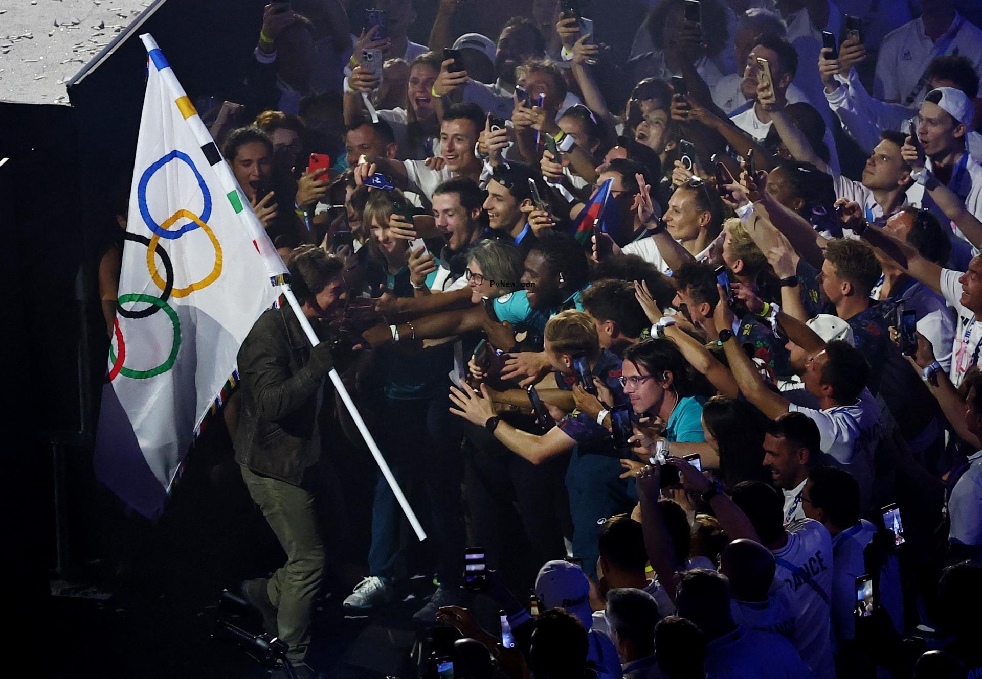 Actor Tom Cruise holds the Olympics flag among athletes during the closing ceremony.