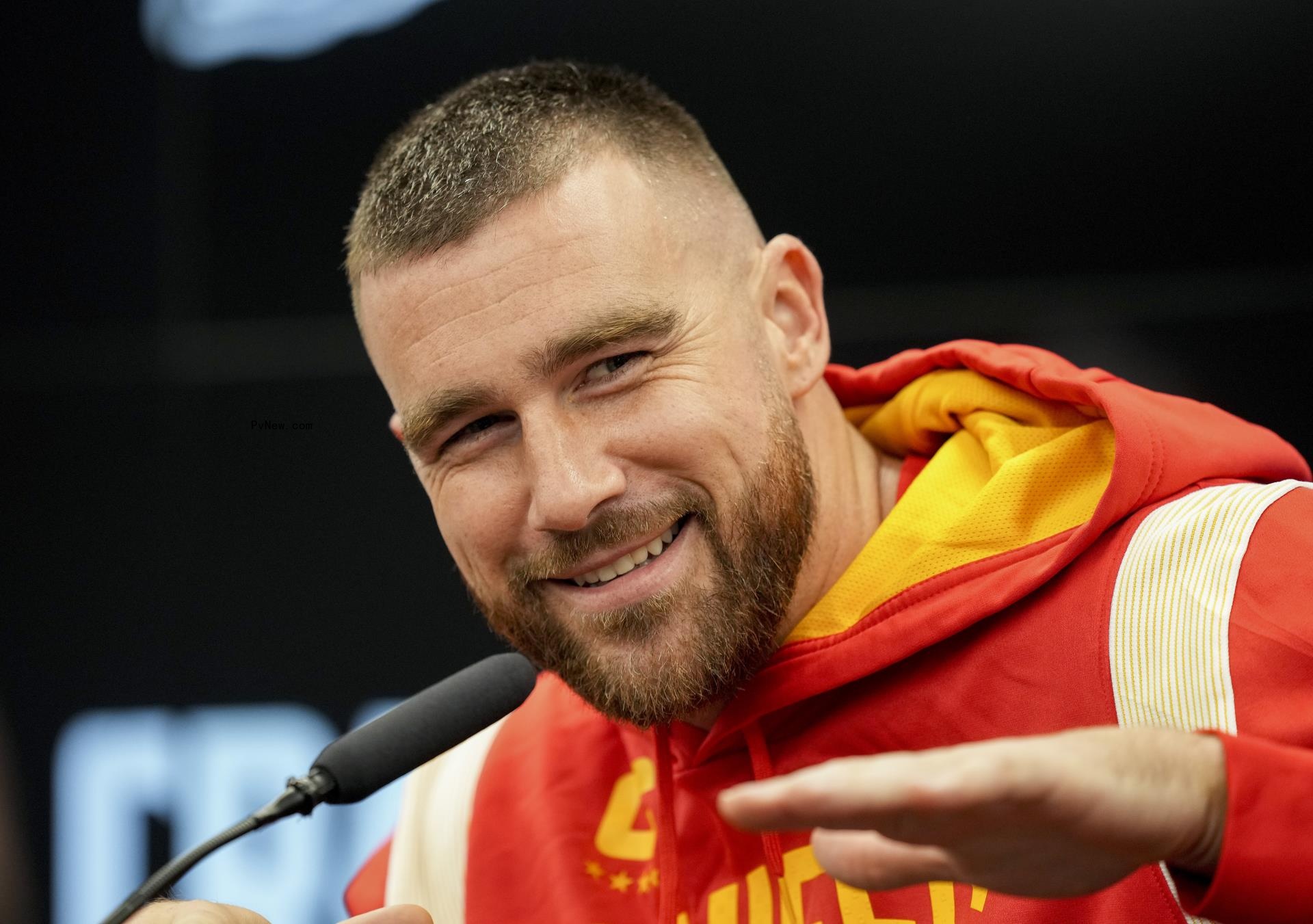 Travis Kelce talking into a microphone