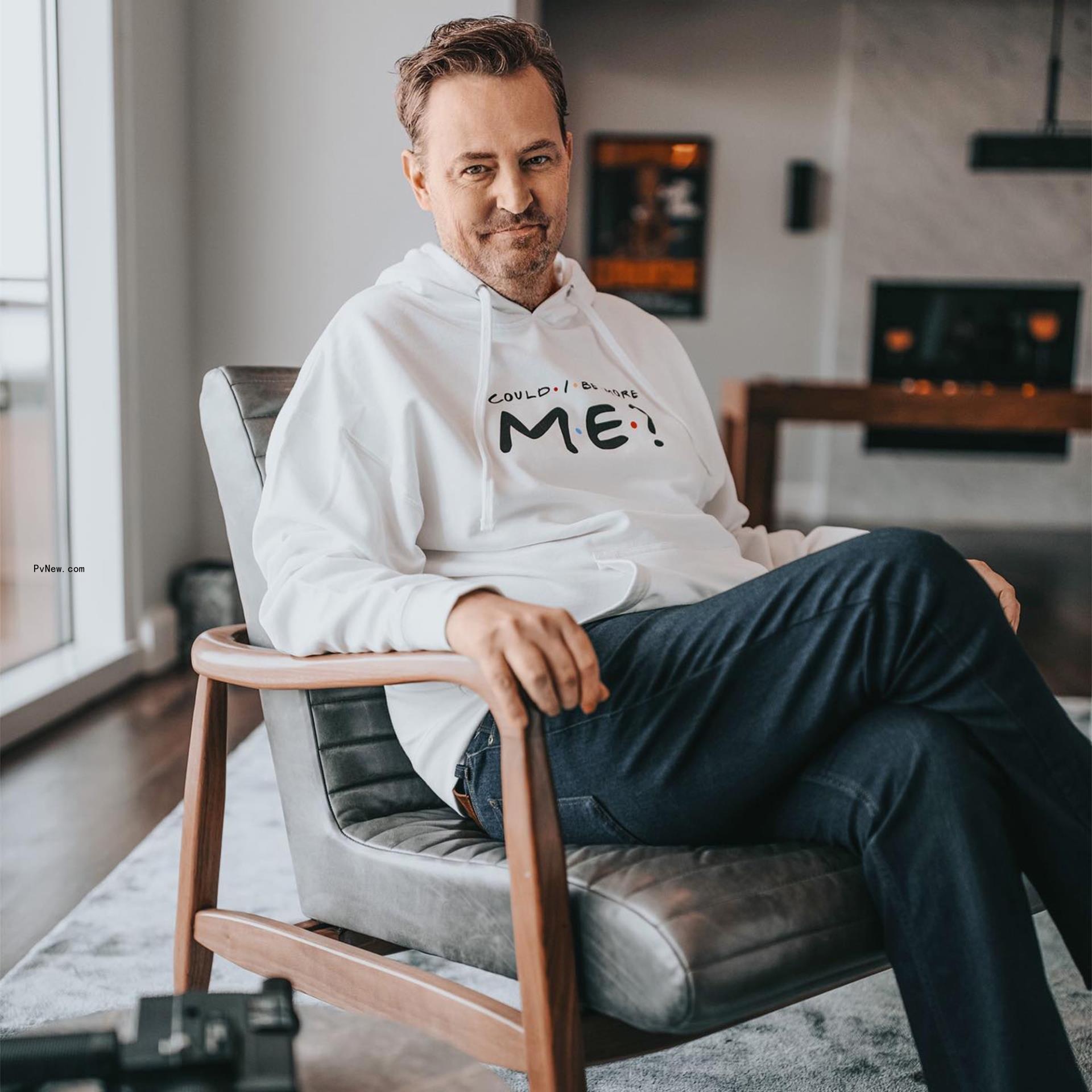 Matthew Perry in a chair wearing his own merchandise 